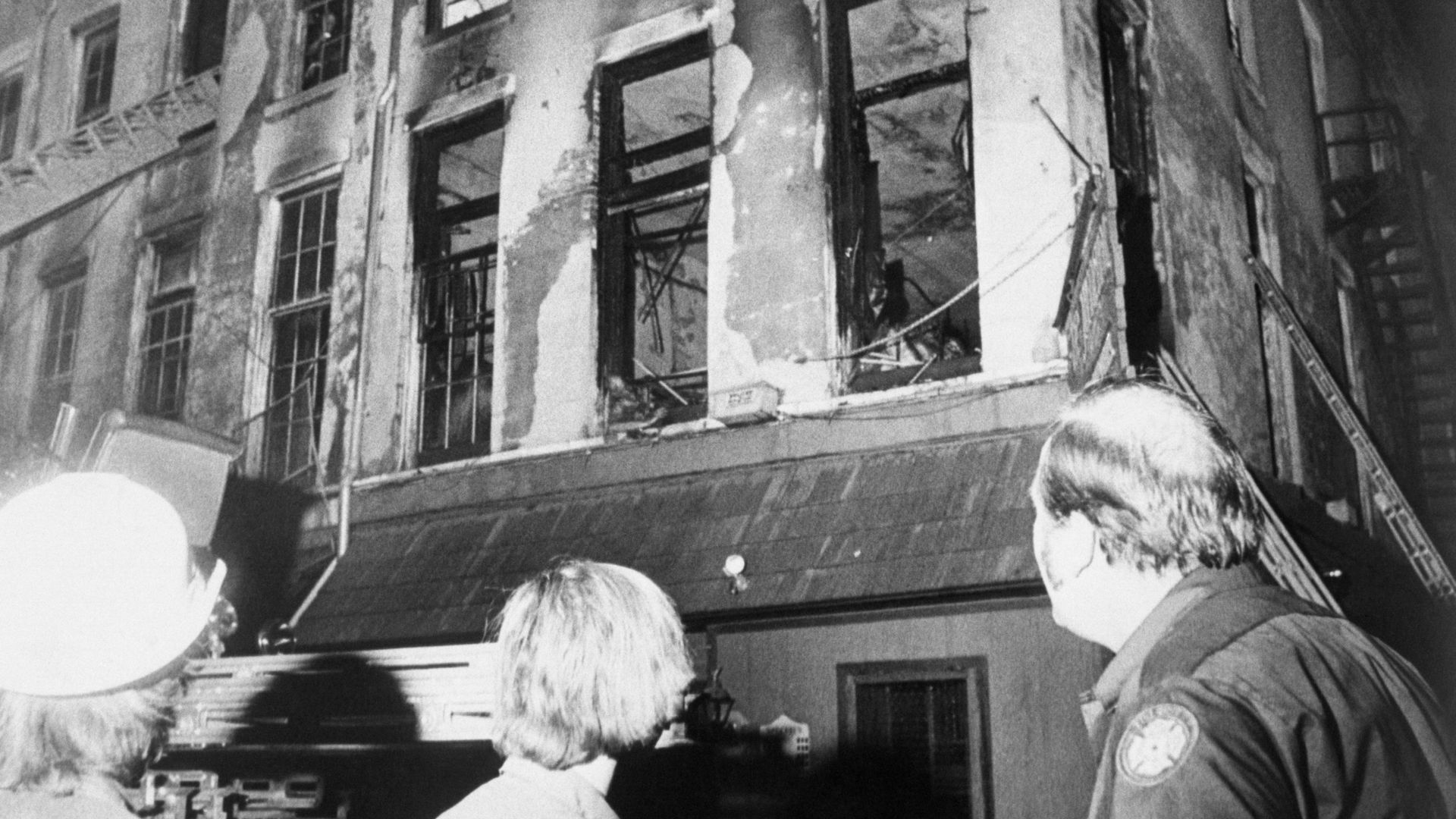 Photos shows firemen and rescue workers looking at the Up Stairs Lounge after a fire ripped through it, eventually killing 32 people.
