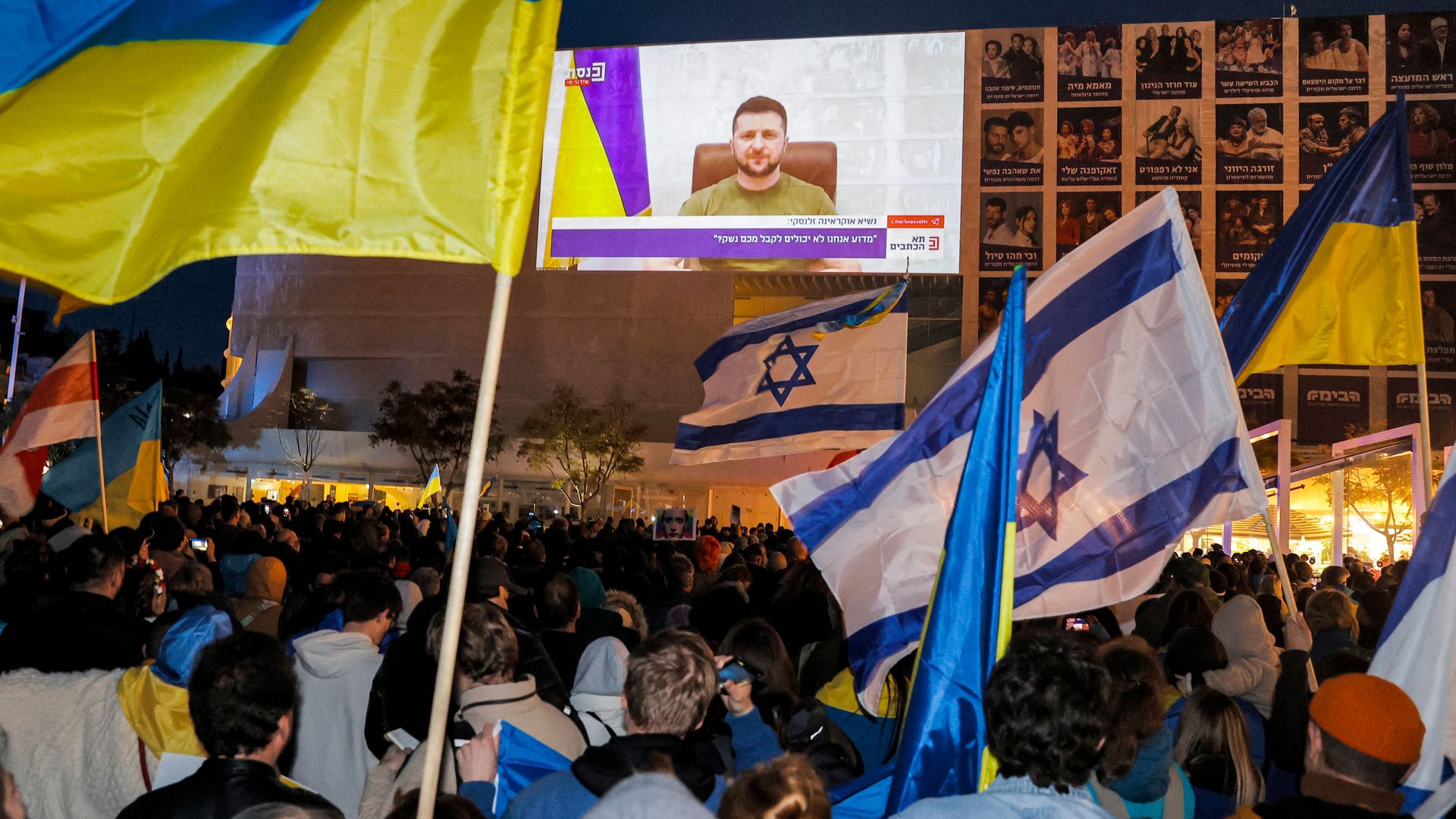People follow the speech by Ukrainian President Volodymyr Zelensky being broadcast outside Habima Theater in Tel-Aviv