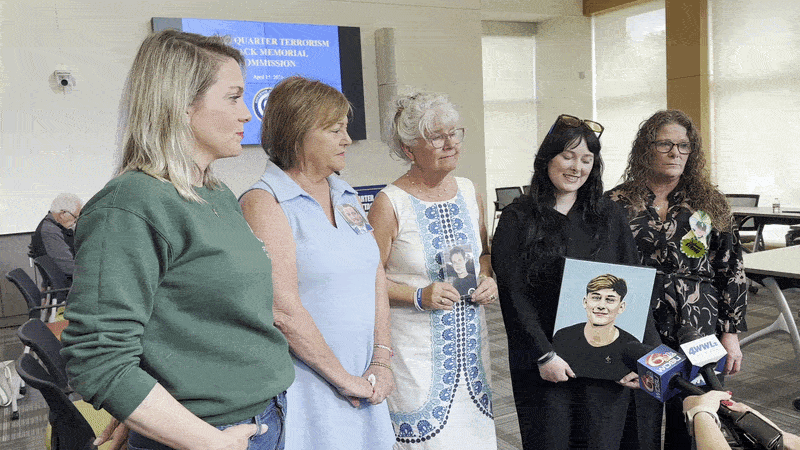 Image shows women holding up photos and paintings of young men while talking to reporters.