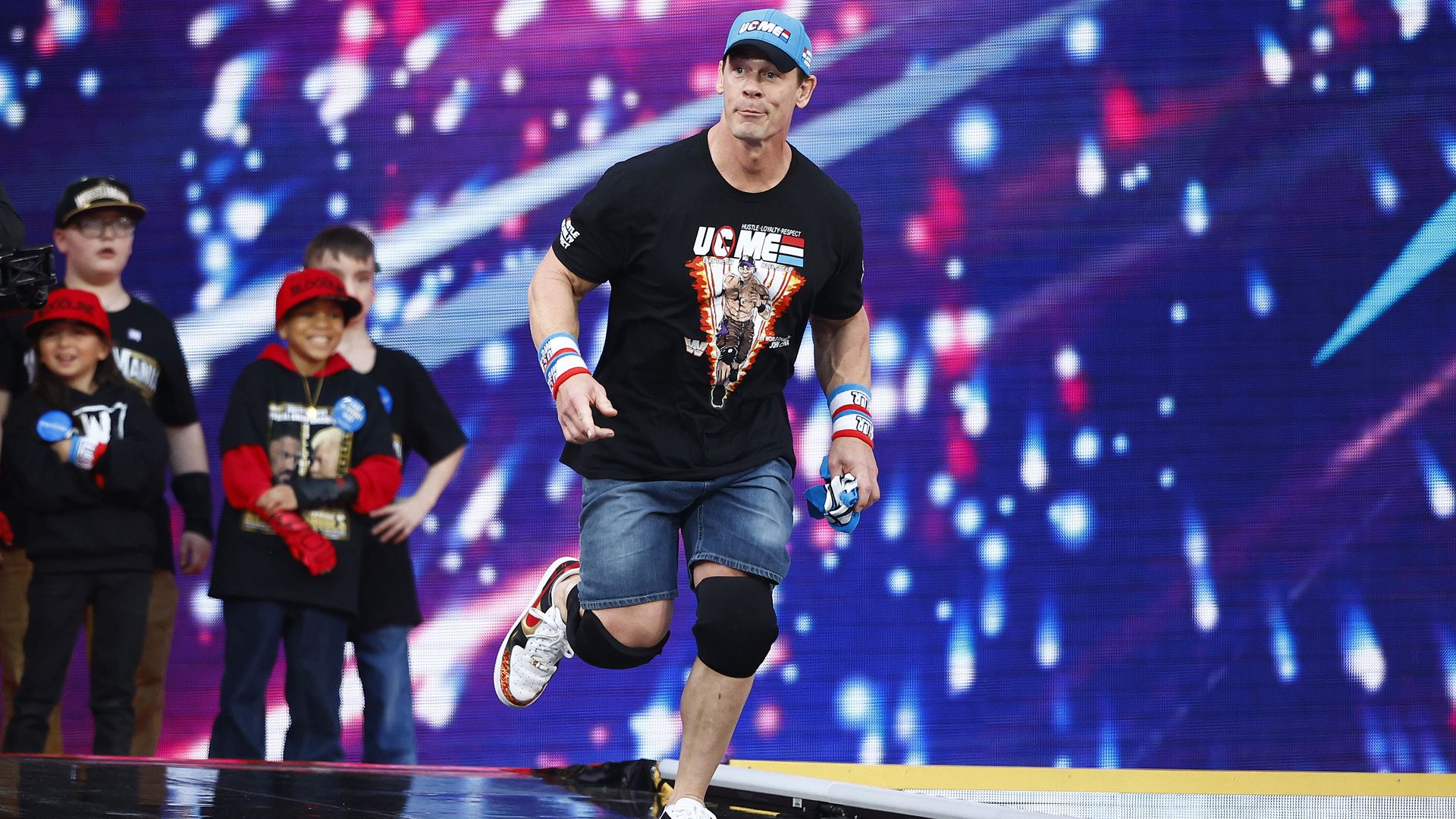 John Cena runs to the ring as smiling kids look on.