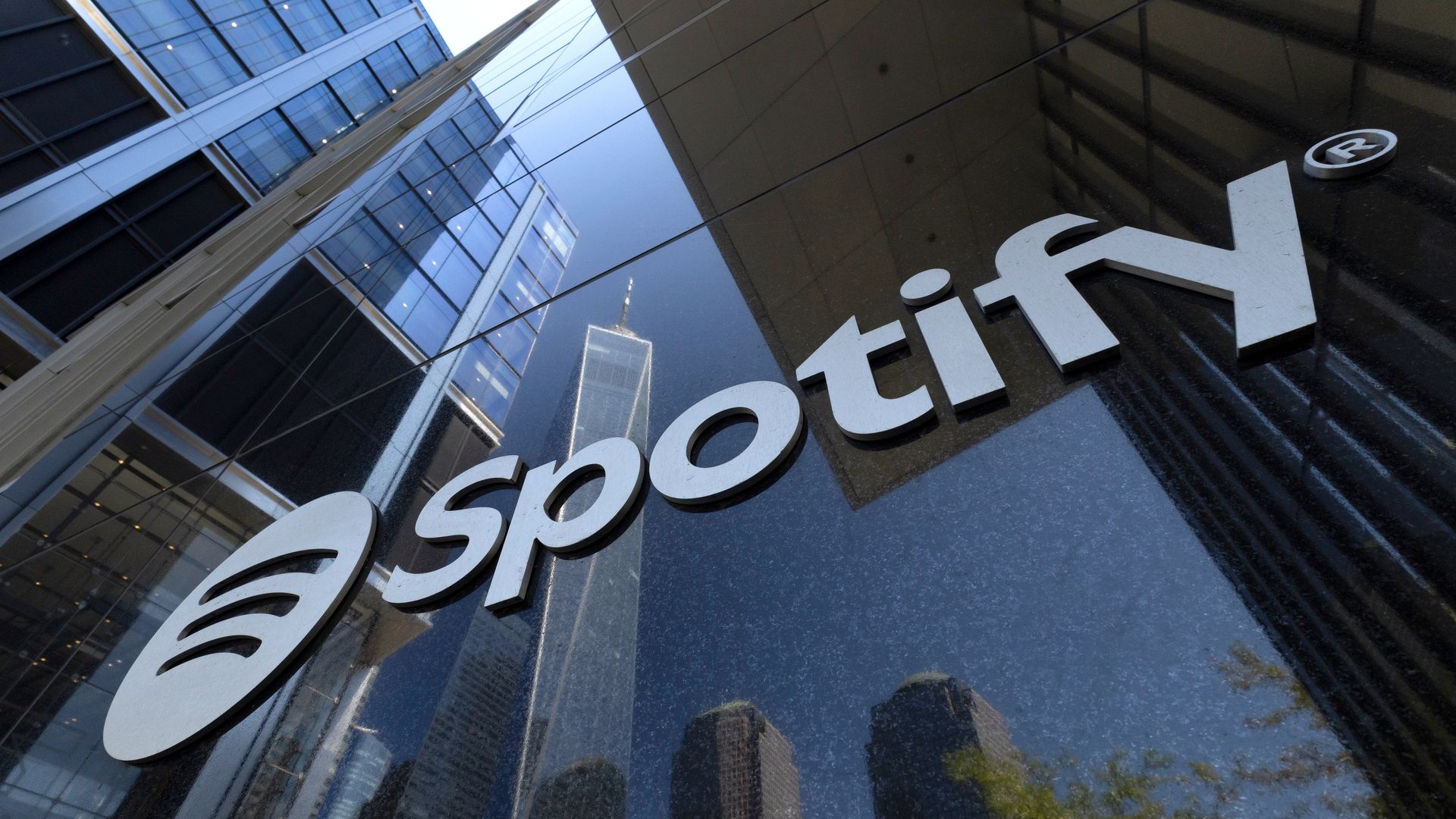 A Spotify corporate logo hangs on the front of its office at 4 World Trade Center as One World Trade Center is reflected in a window on Sept. 7, 2026, in New York City..