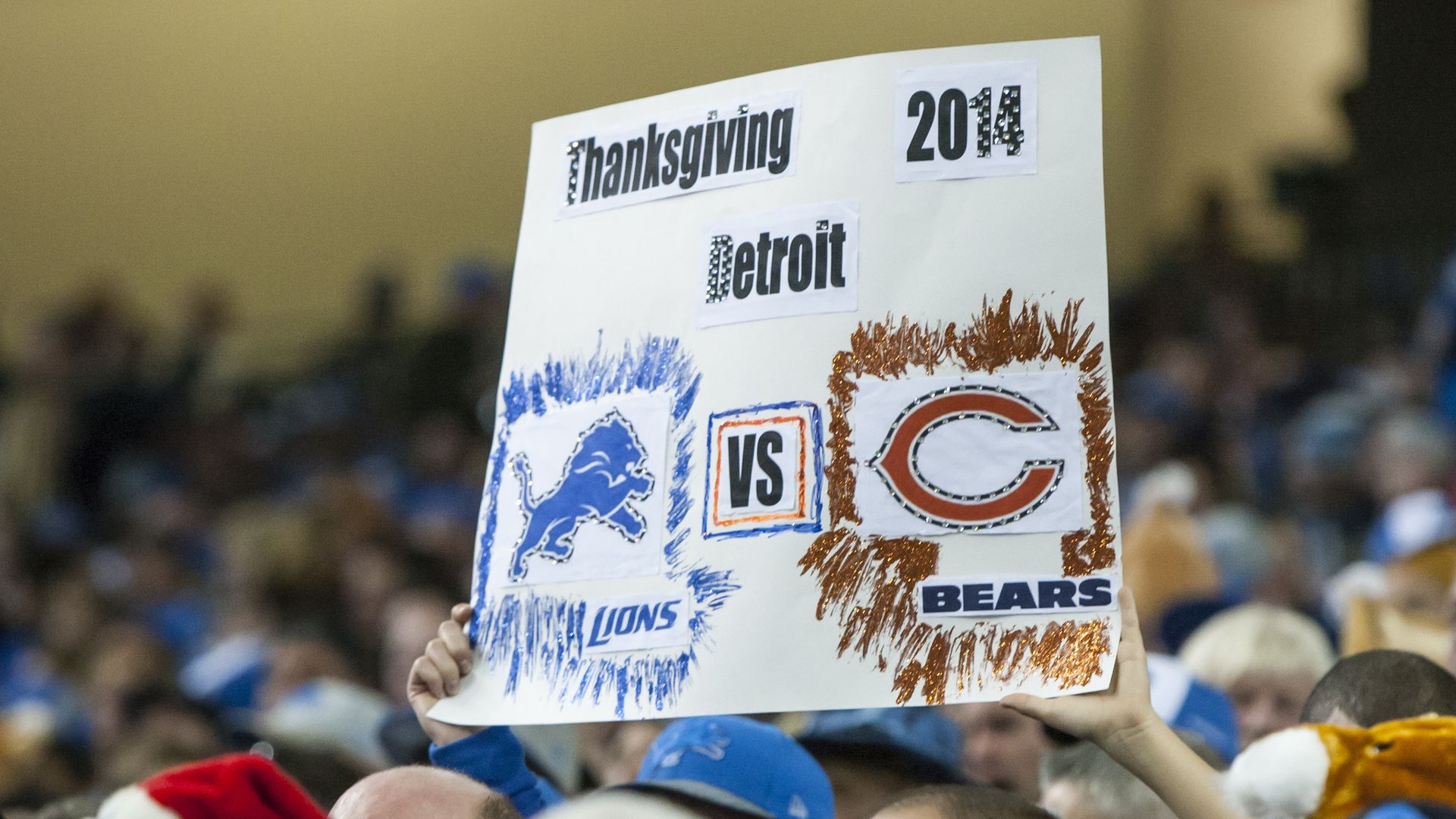 Photo of a poster that says "Thanksgiving 2014 Detroit" at a football game 