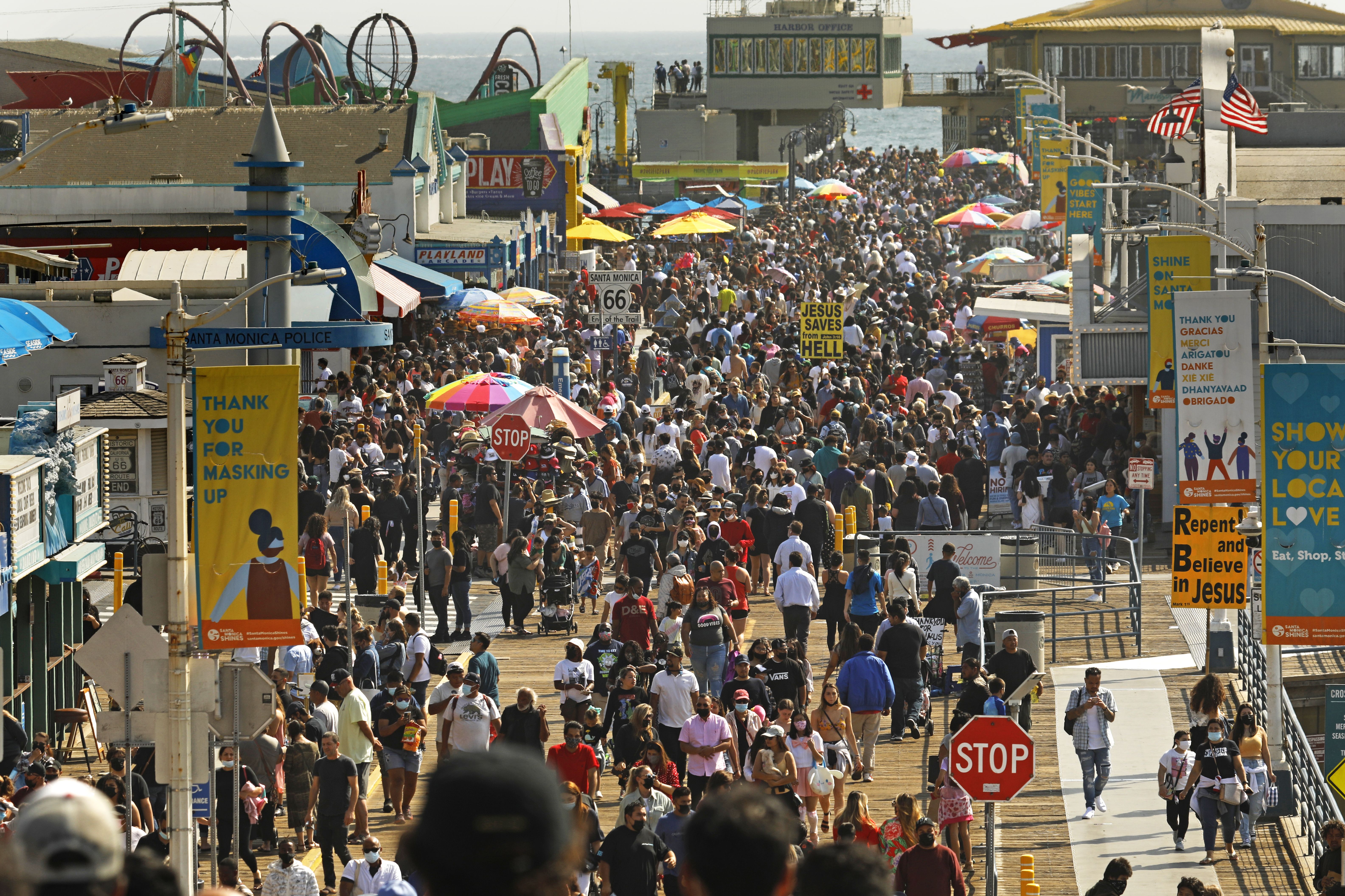 A crowd of people walk down a boardwalk