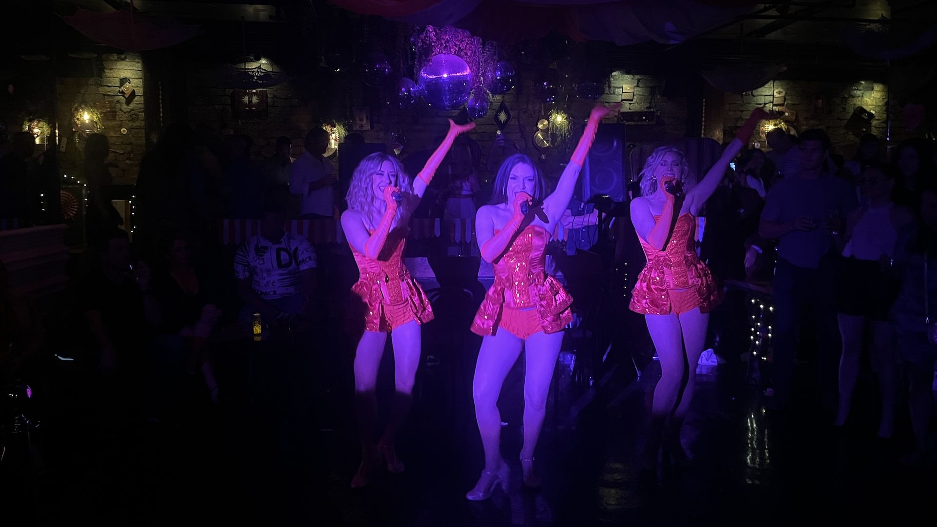 Dancers in red, sequined outfits perform a burlesque-inspired cabaret show.