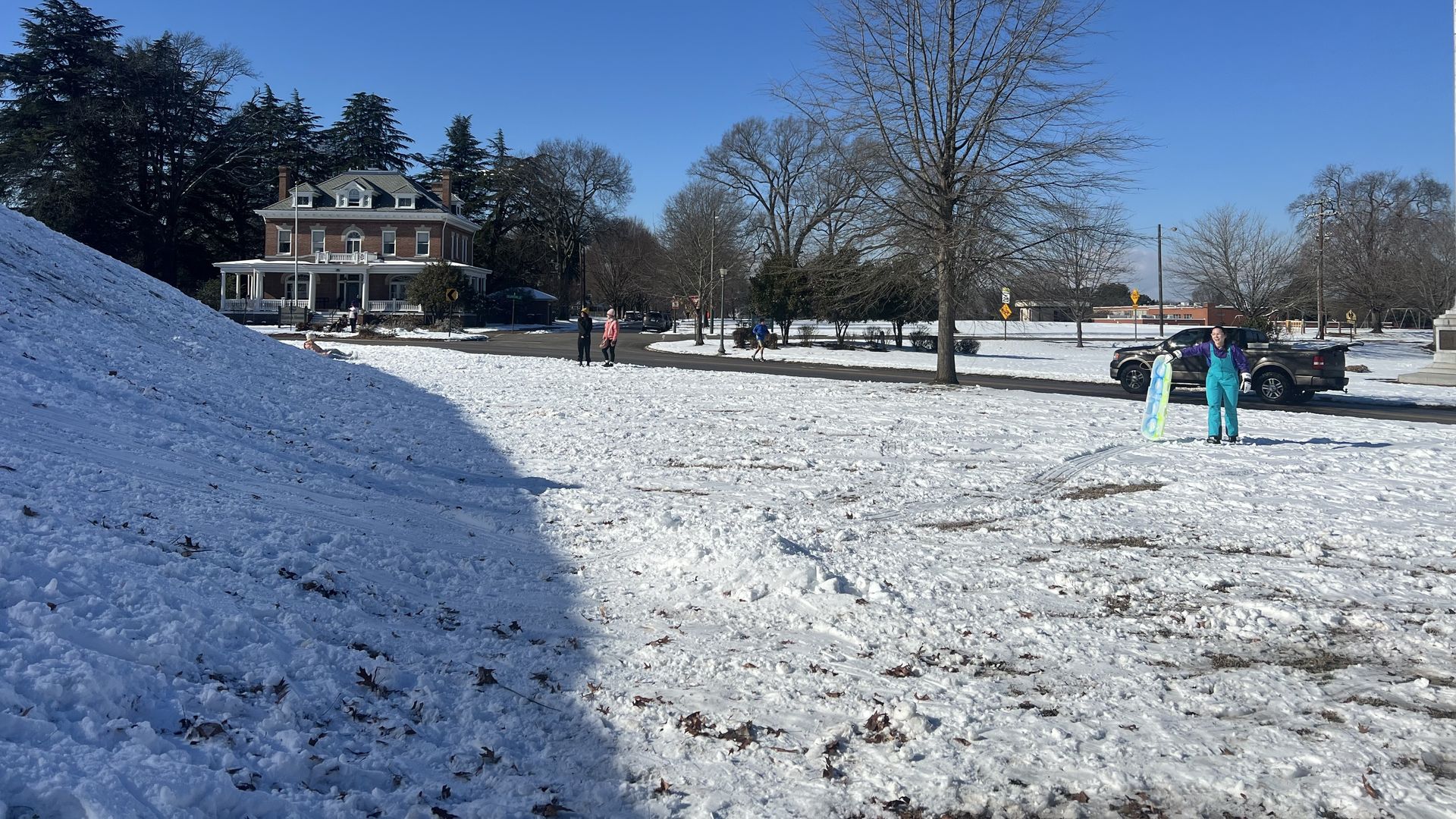 A snowy hill in richmond with sleigh riders standing by 