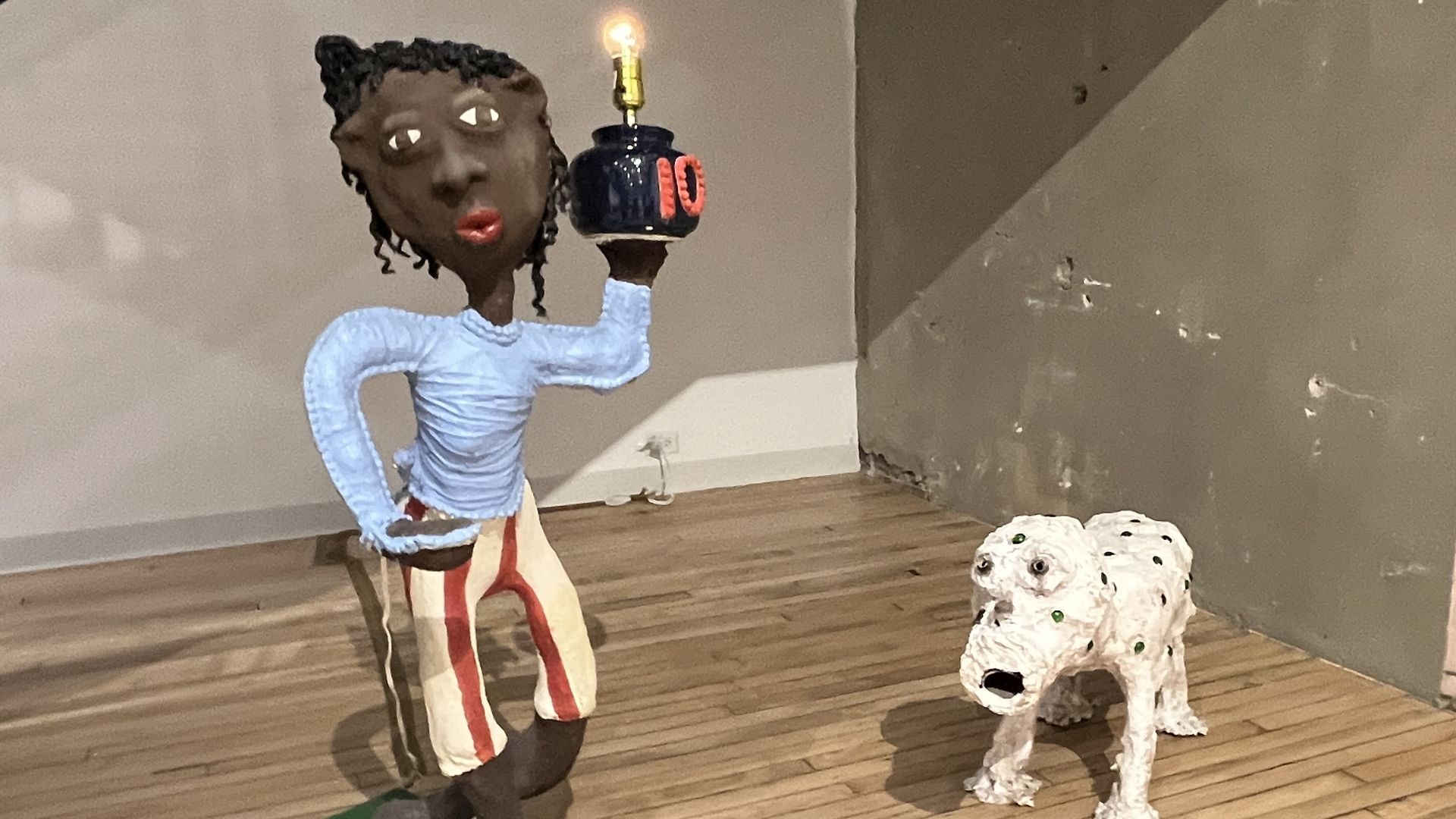 Sculpture of a young Black woman with a blue shirt and striped pants