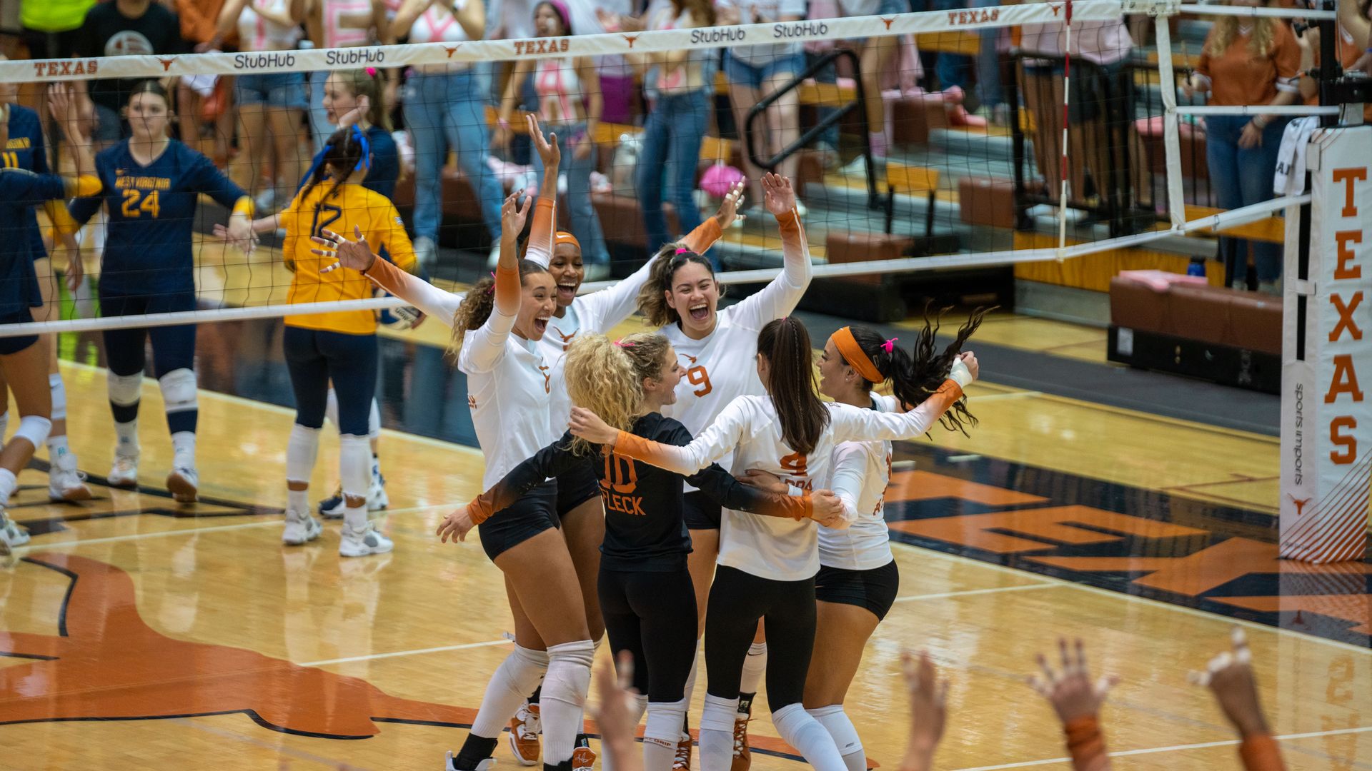 The University of Texas volleyball team huddles in triumph during a match at Gregory Gym. 