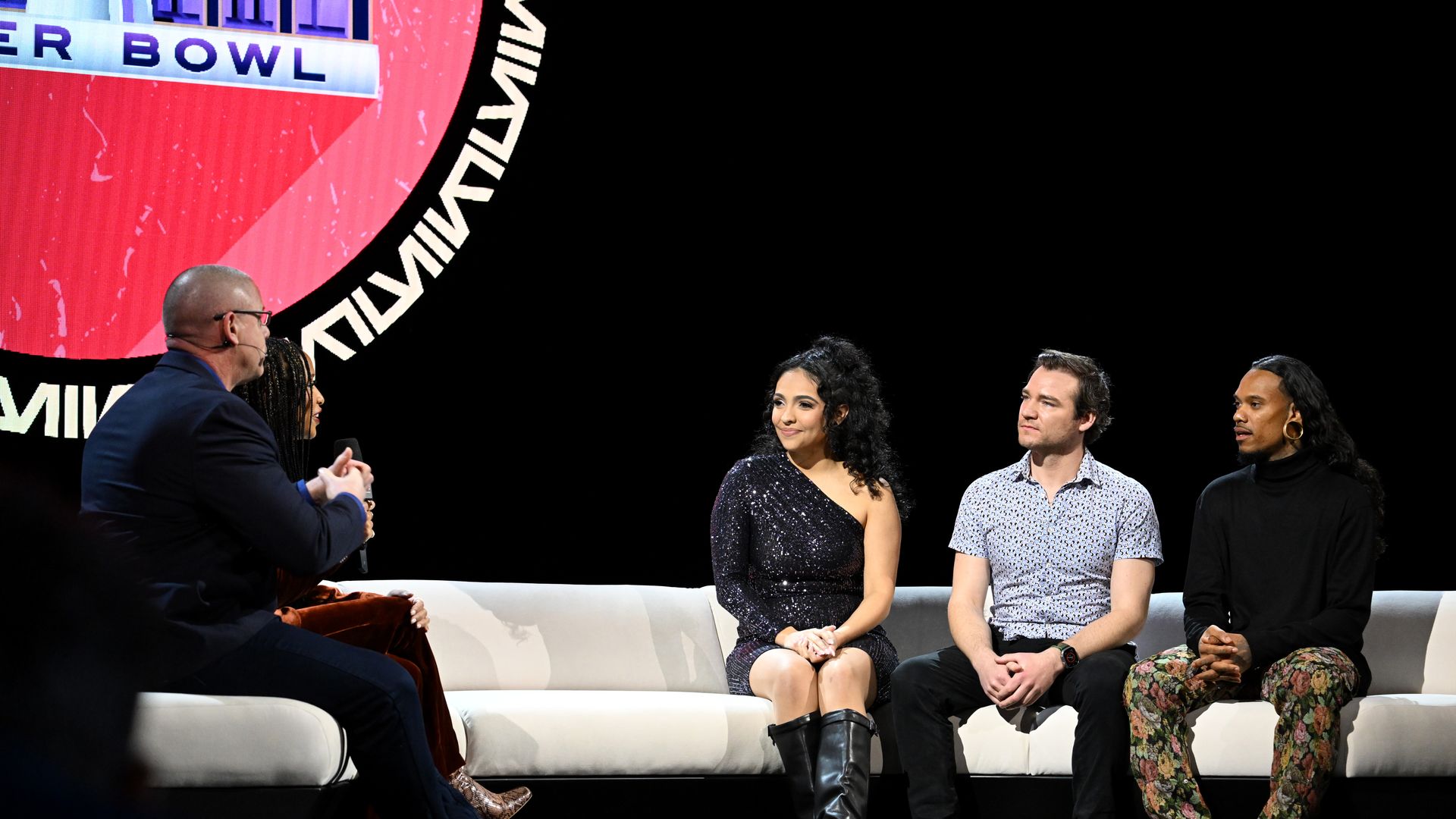 Three people are seated on a couch being interviewed