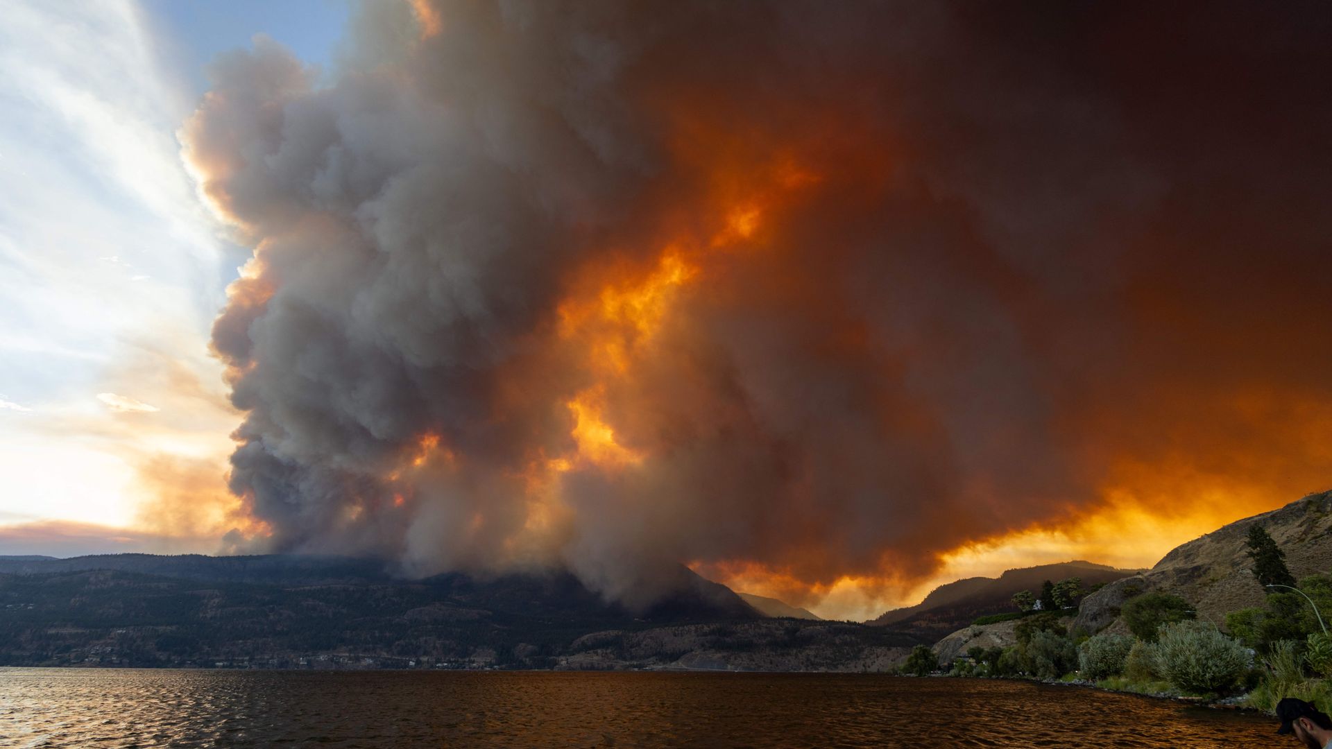 Photo of a forest fire seen across a lake in Canada during wildfires in 2023.