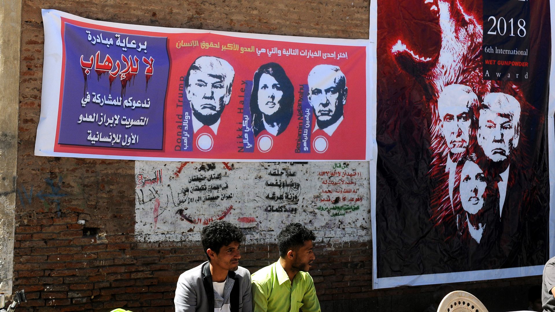 Two Yemeni men under banners showing Donald Trump, Benjamin Netanyahu, and Nikki Haley. 