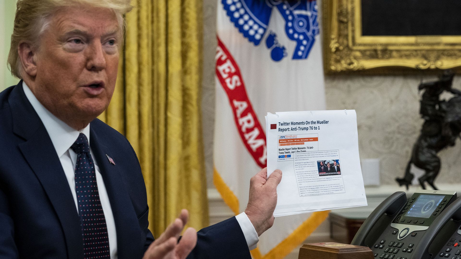 A photo of President Trump holding up a paper before signing a social media executive order