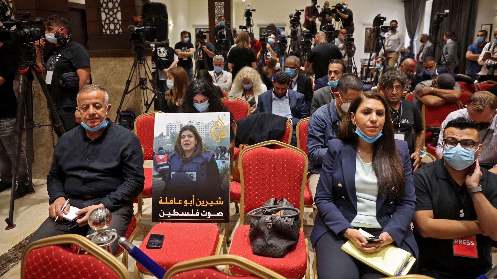 A photo of slain US-Palestinian correspondent Shireen Abu Akleh, with a caption in Arabic reading "Shireen Abu Akleh, the voice of Palestine", is placed amongst reporters