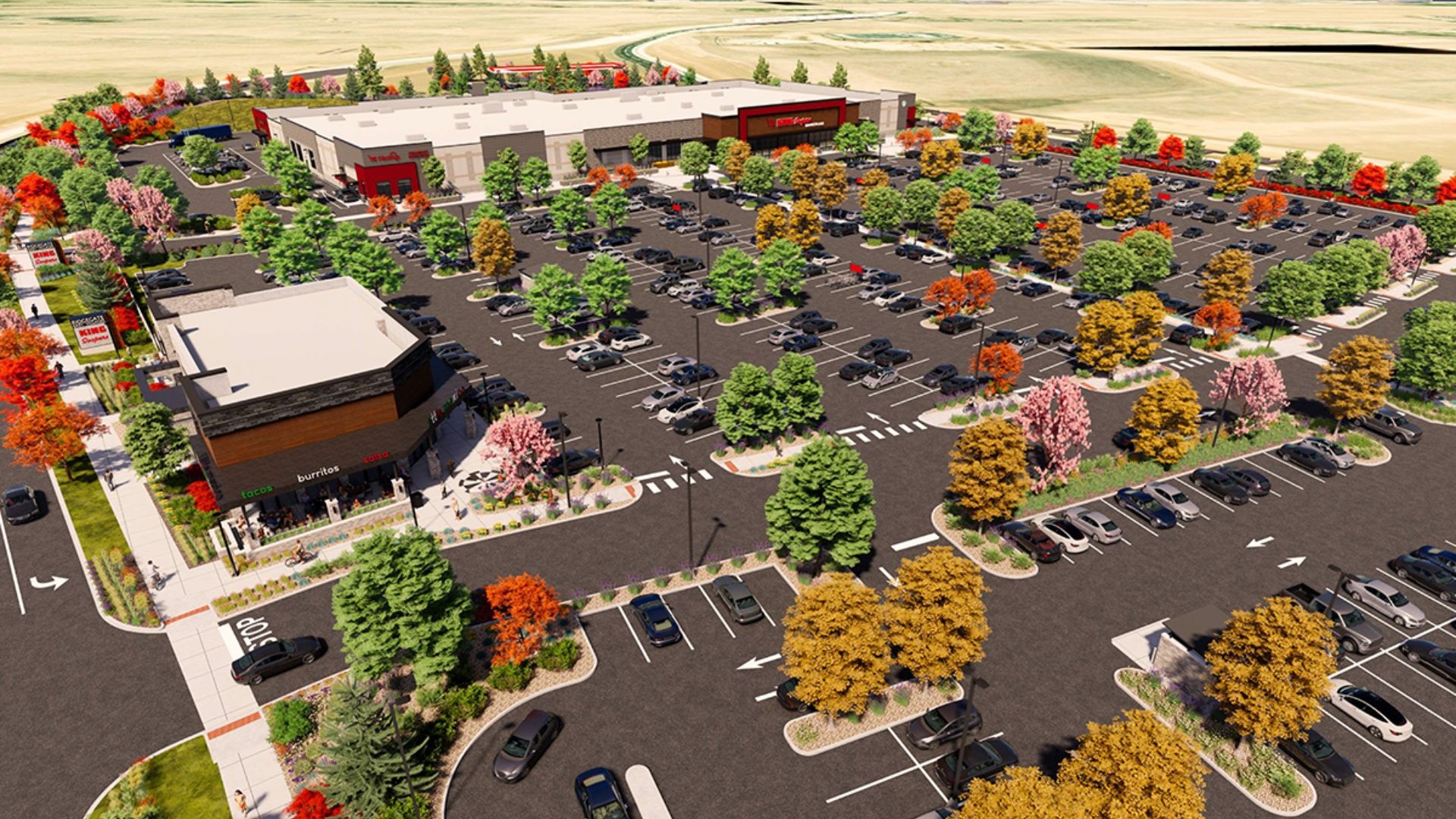 Bird's-eye view of a large shopping center with a sprawling parking lot filled with cars, colorful autumn trees, and several retail buildings; foreground features a taco/burrito restaurant.