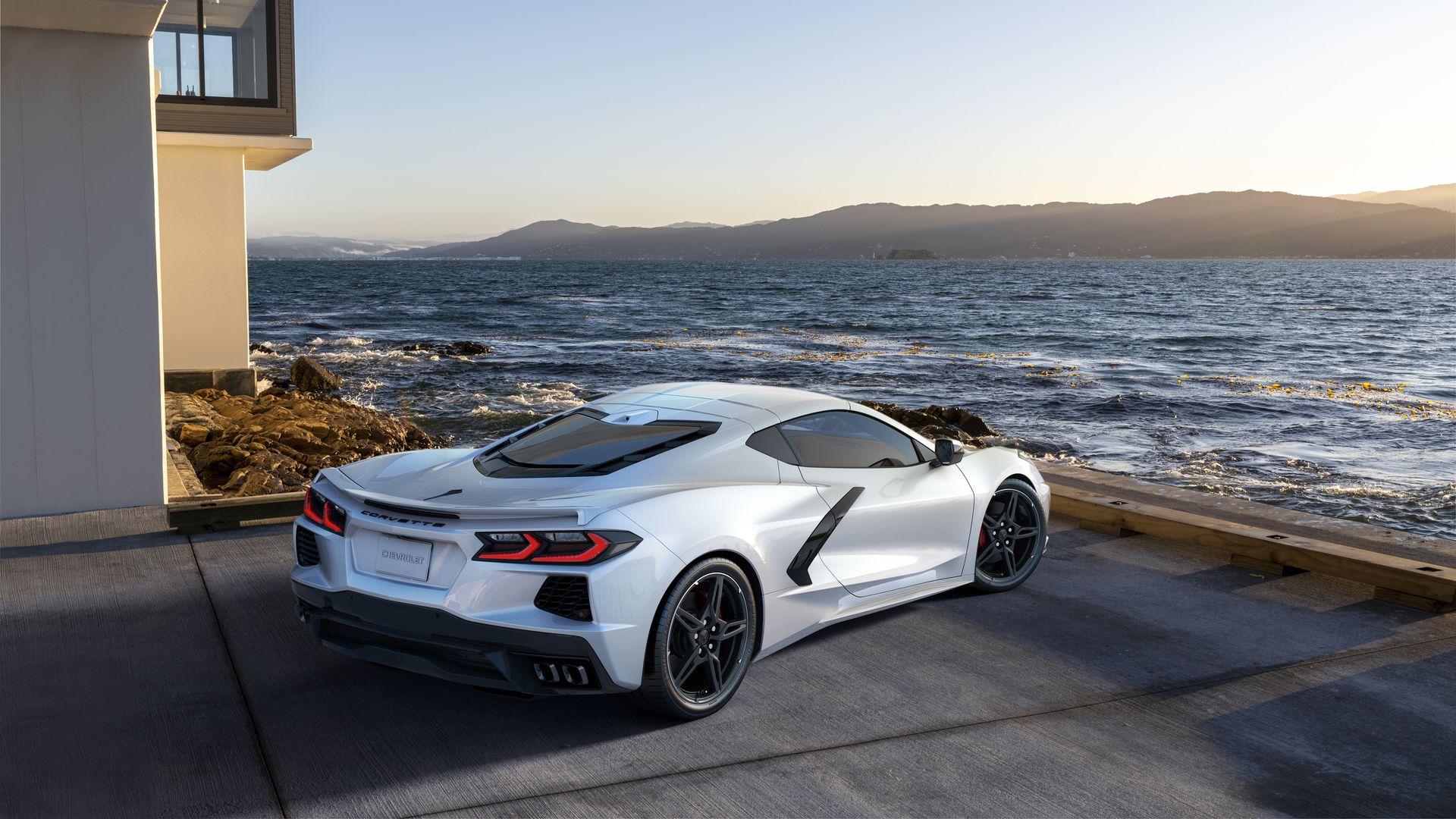 A silver sports car sits on an elevated deck overlooking the earth below