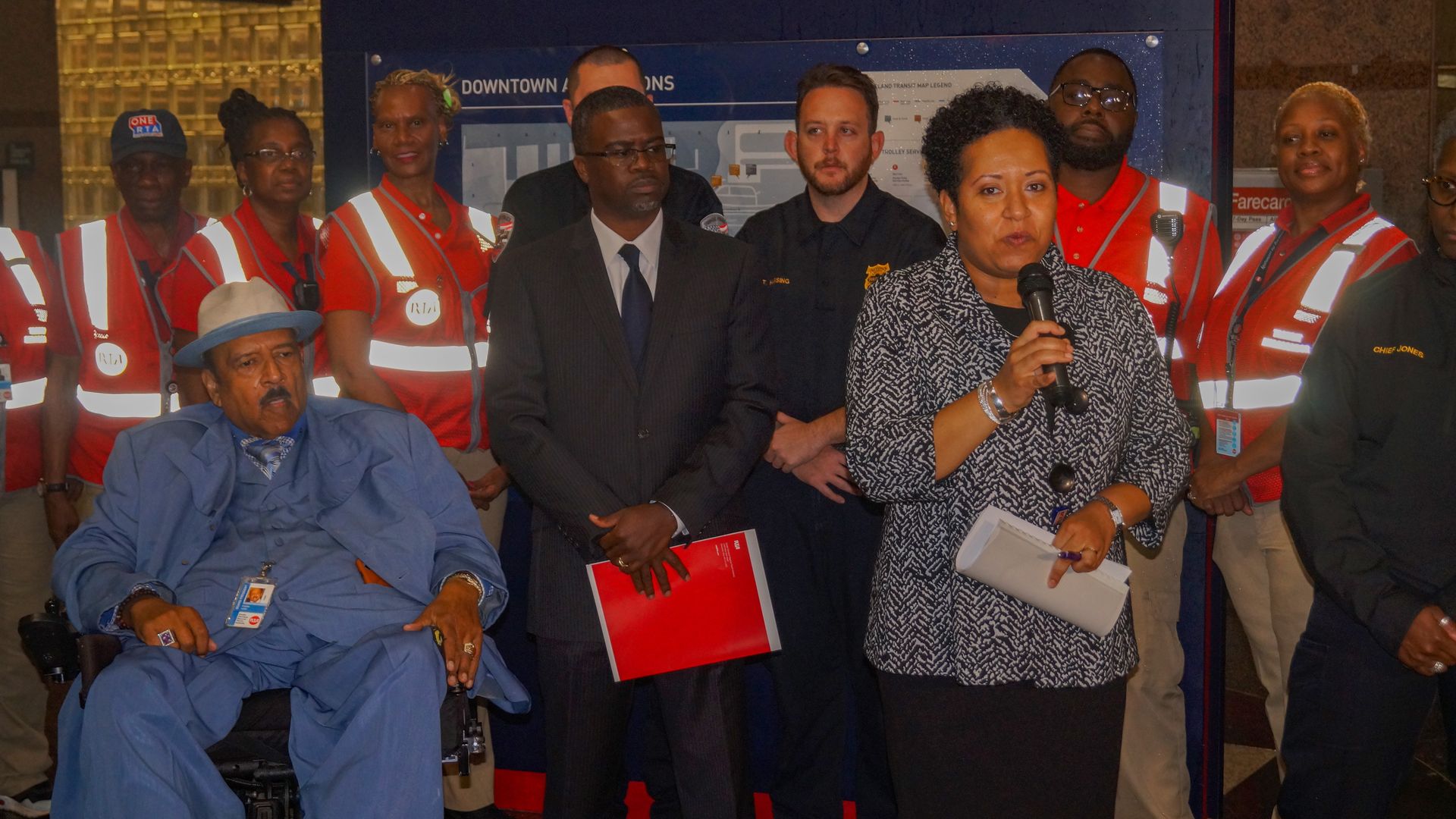 RTA CEO India Birdsong Terry holds a microphone, backed by people in red safety vests.