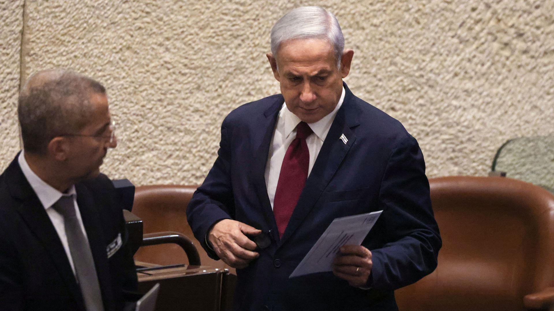 Israeli Prime Minister Benjamin Netanyahu standing next to a lawmaker in the Knesset