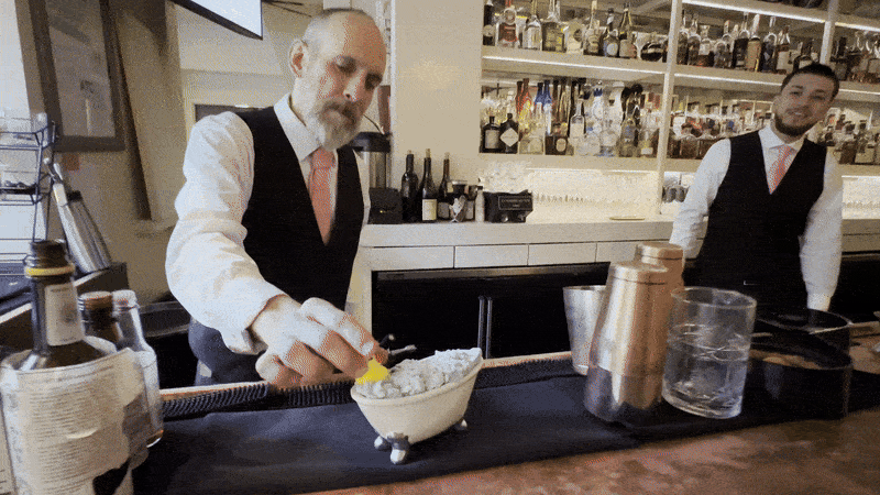 Image shows a bartender adding a rubber ducky to a bathtub cocktail.