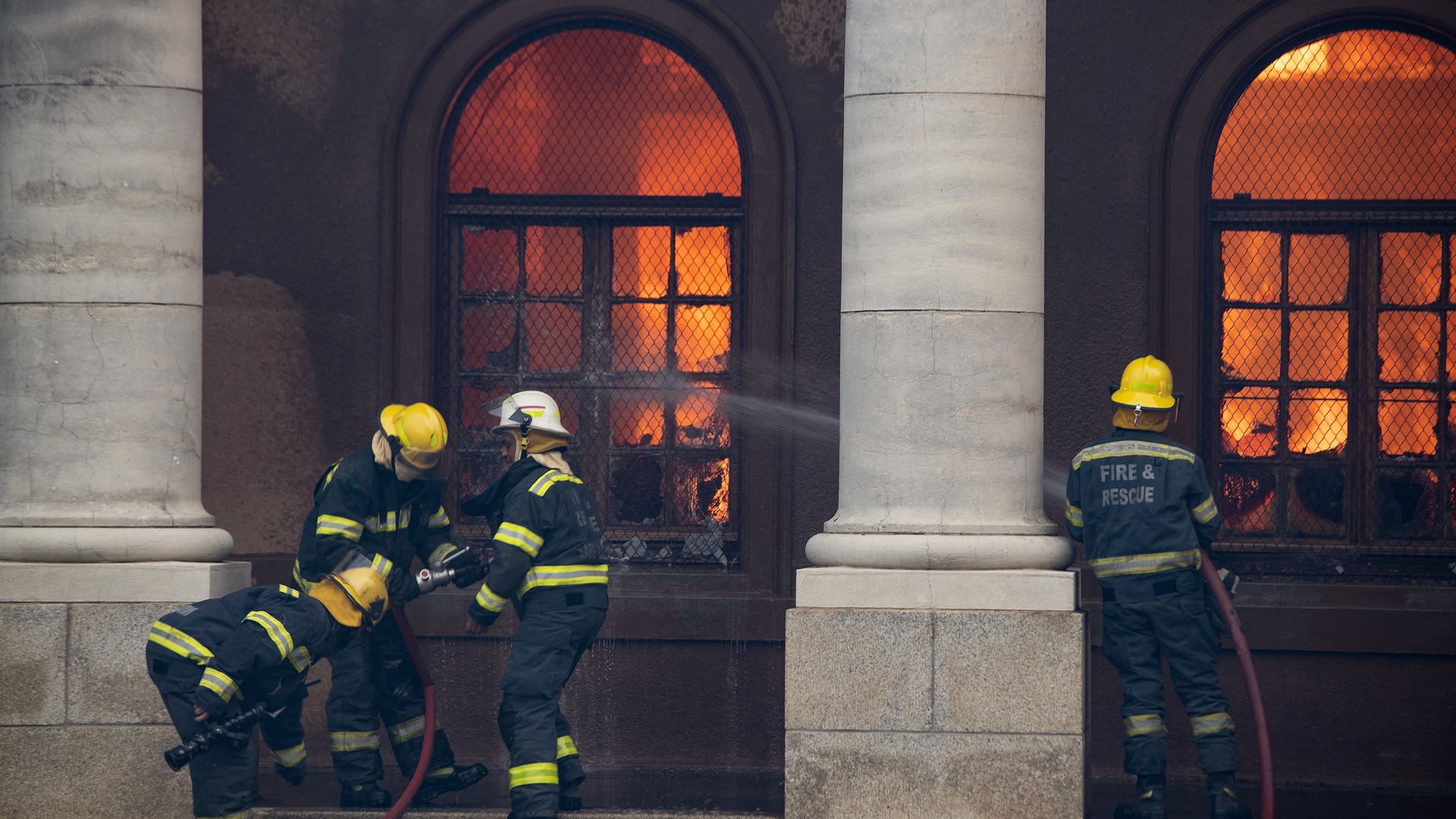 Firefighters try to extinguish a fire in the Jagger Library, at the University of Cape Town, after a forest fire came down the foothills of Table Mountain on April 18
