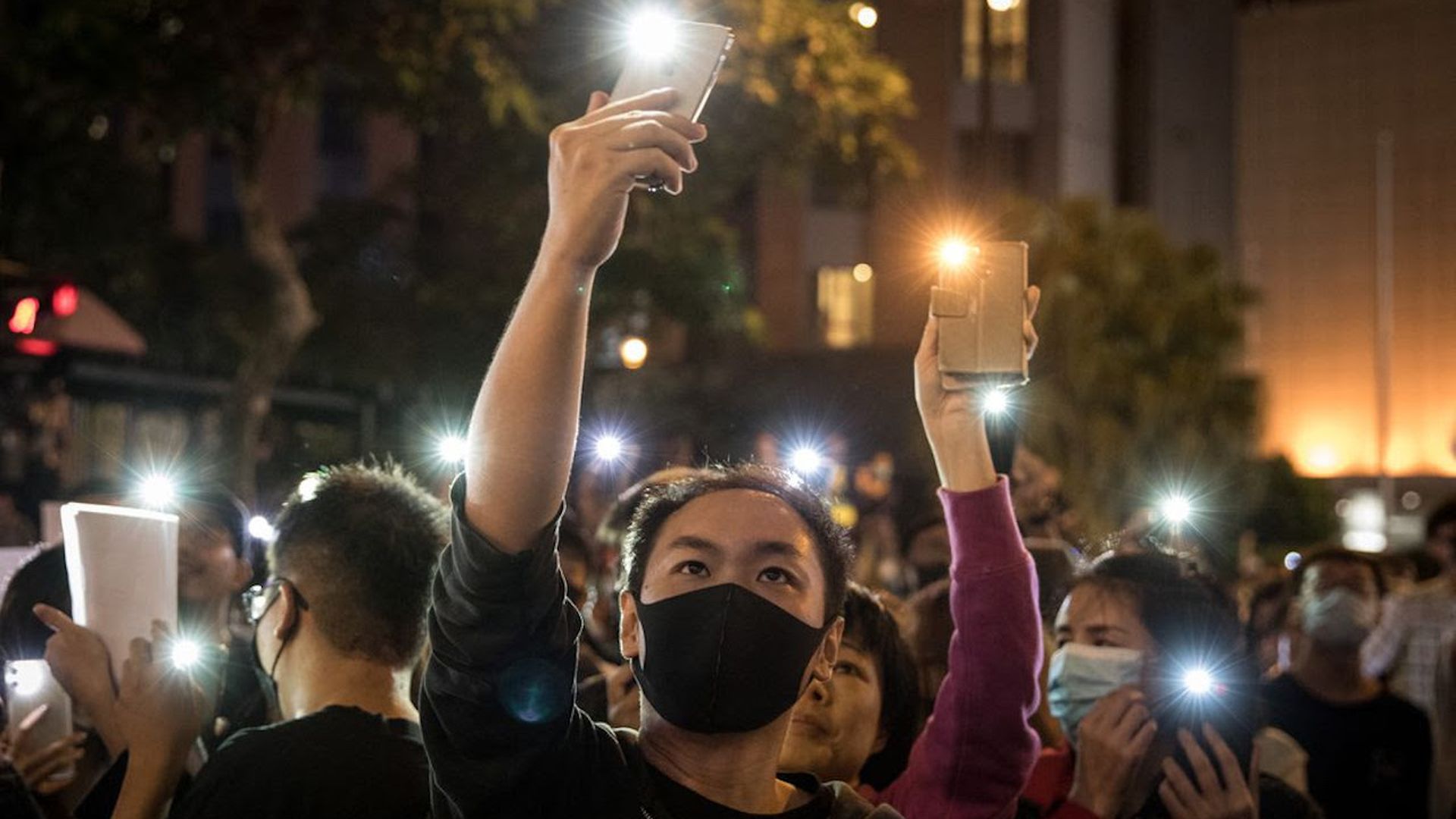 Anti-government protesters shine phone lights at police as they chant slogans in Hong Kong yesterday