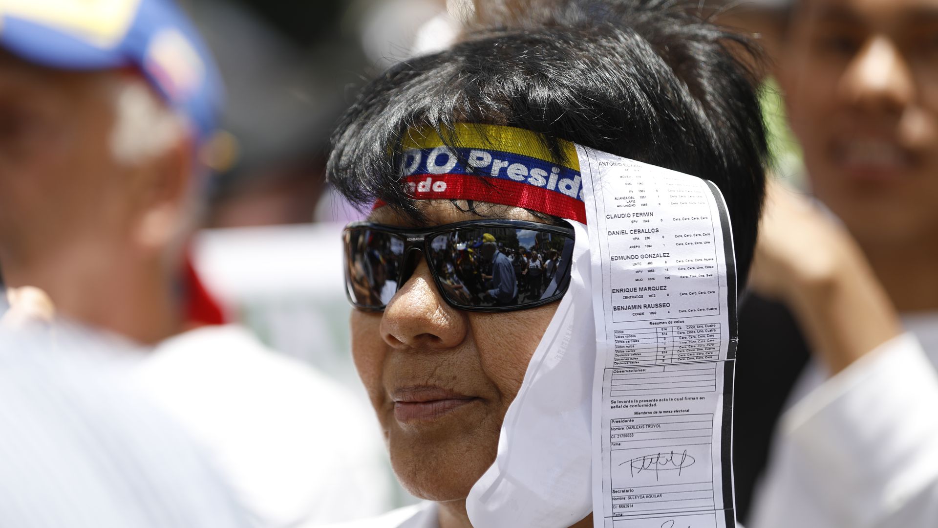 A protester has a paper receipt with vote tallies hanging from a headband in Caracas, Venezuela. 