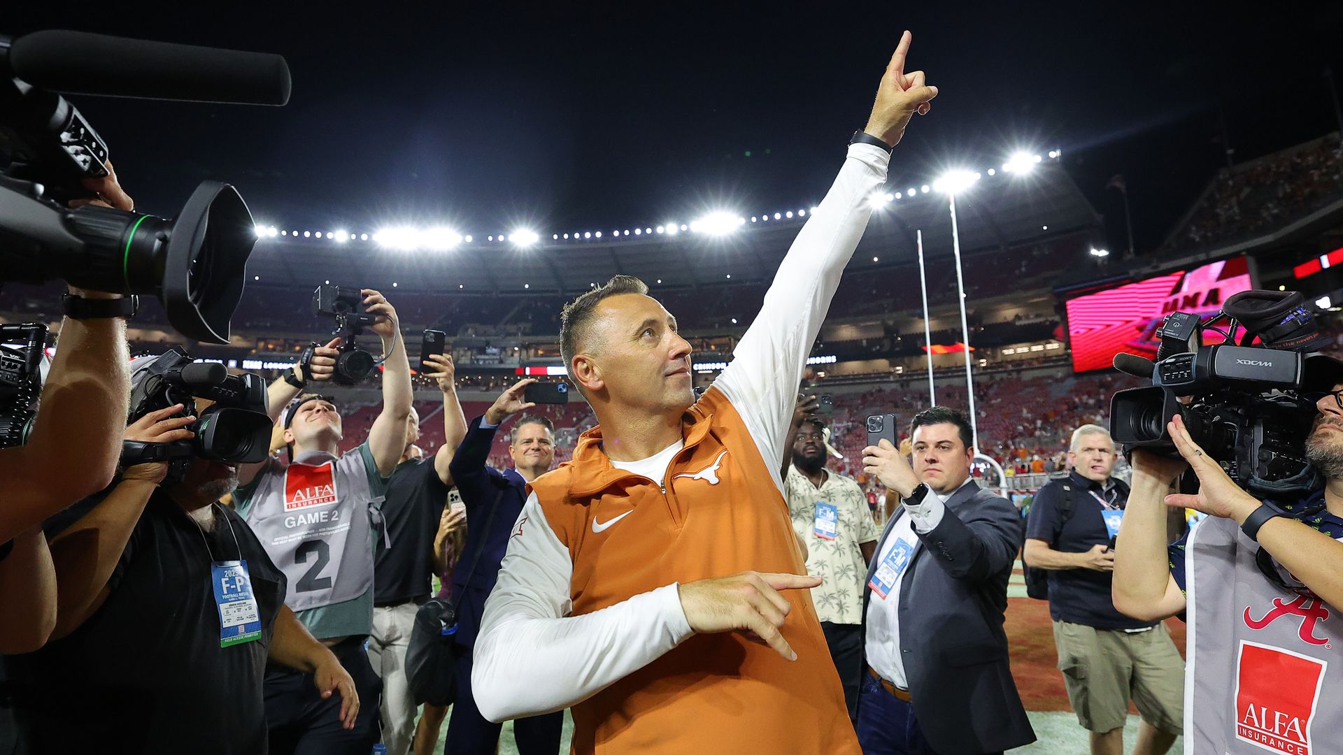 Steve Sarkisian gestures triumphantly to a crowd.