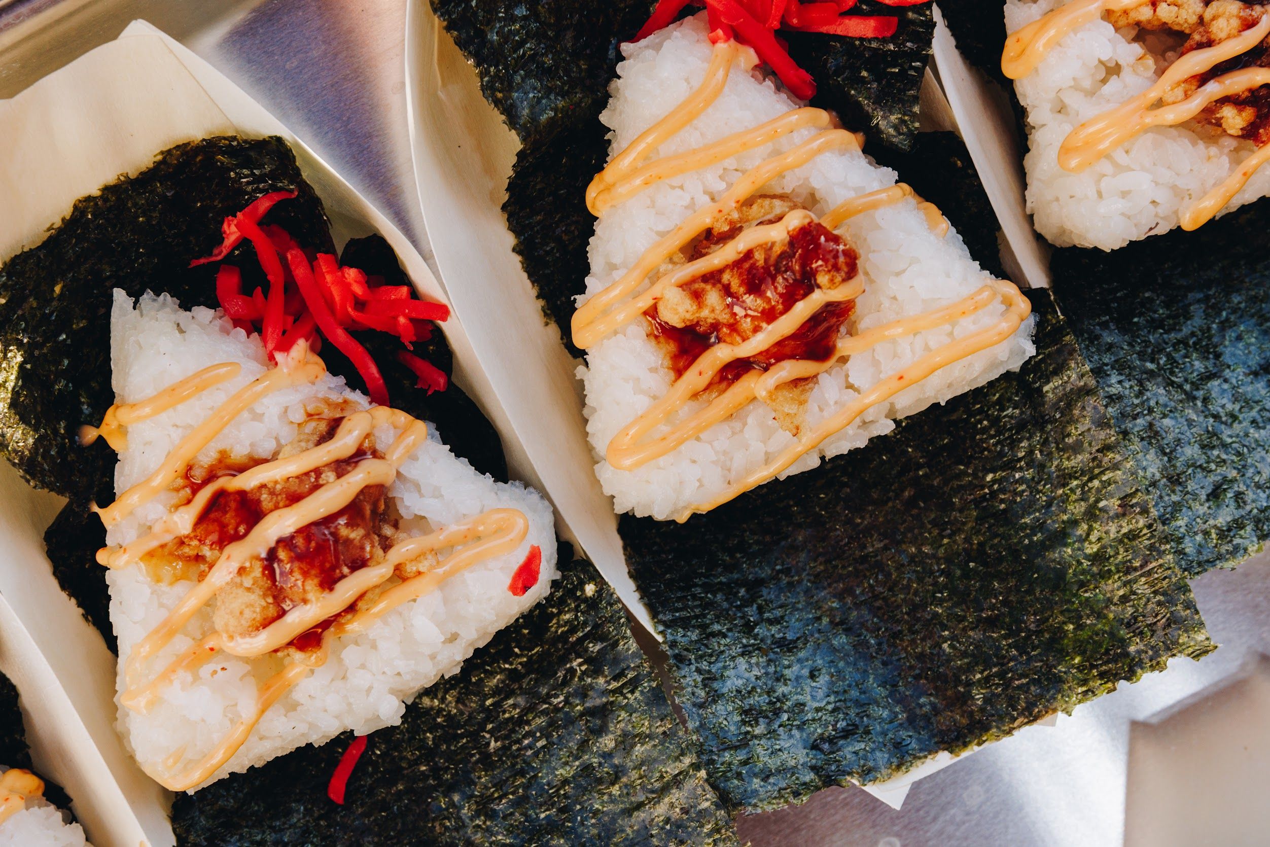Sushi portions with drizzled sauce on plates.