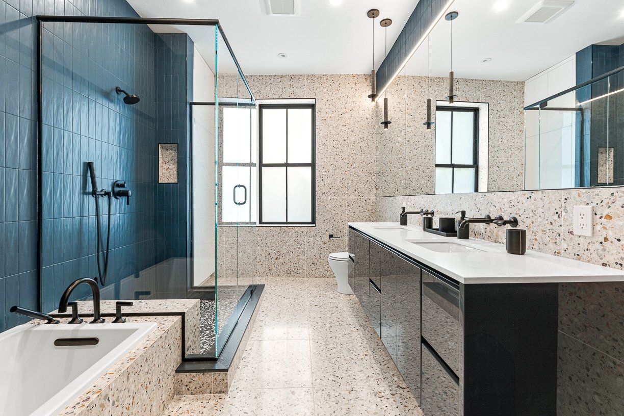 A real estate photo showing one of four full bathrooms in 31 Monument Square in Charlestown. One wall has dark blue-green tile. 