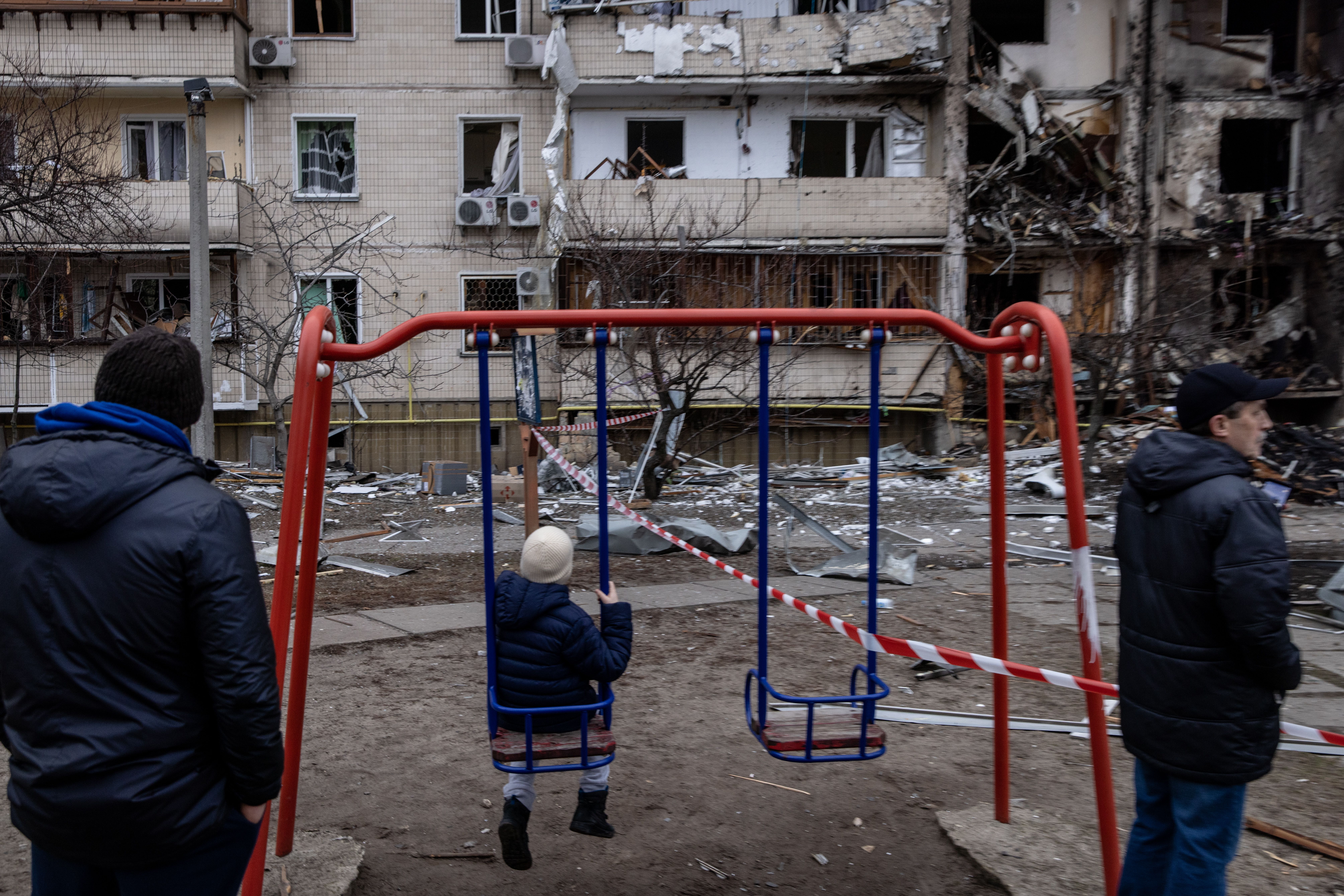 A boy plays on a swing in front of a damaged residential block hit by a missile strike on Feb. 25.