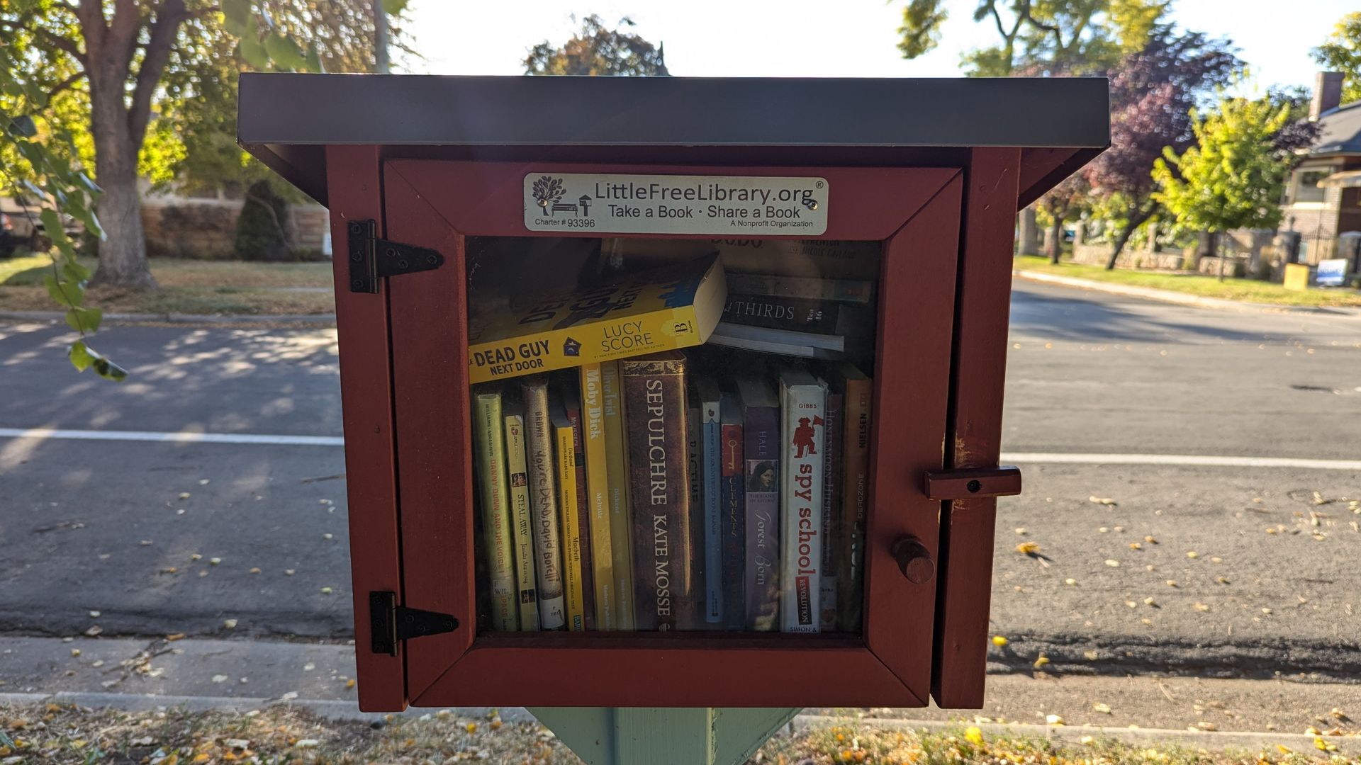A wooden box with a glass door houses a about a dozen books in a "little free library."