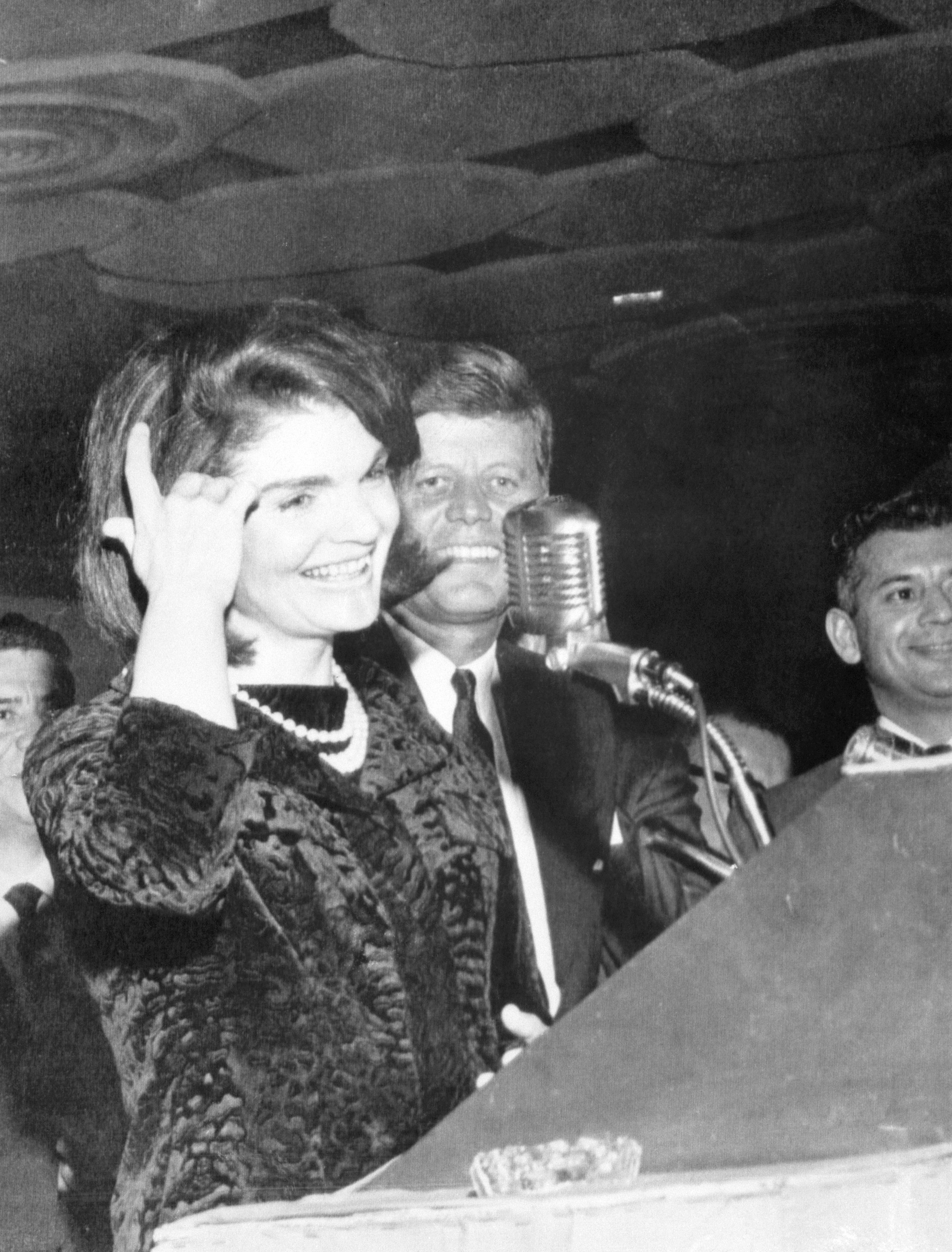 First Lady Jackie Kennedy smiles at the crowd in Houston as the president stands beside her on November 21, 1963. Mrs. Kennedy amused the audience of Mexican American civil rights leaders with the League of United Latin American Citizens, by speaking Spanish. The next day the president will be killed in Dallas. 