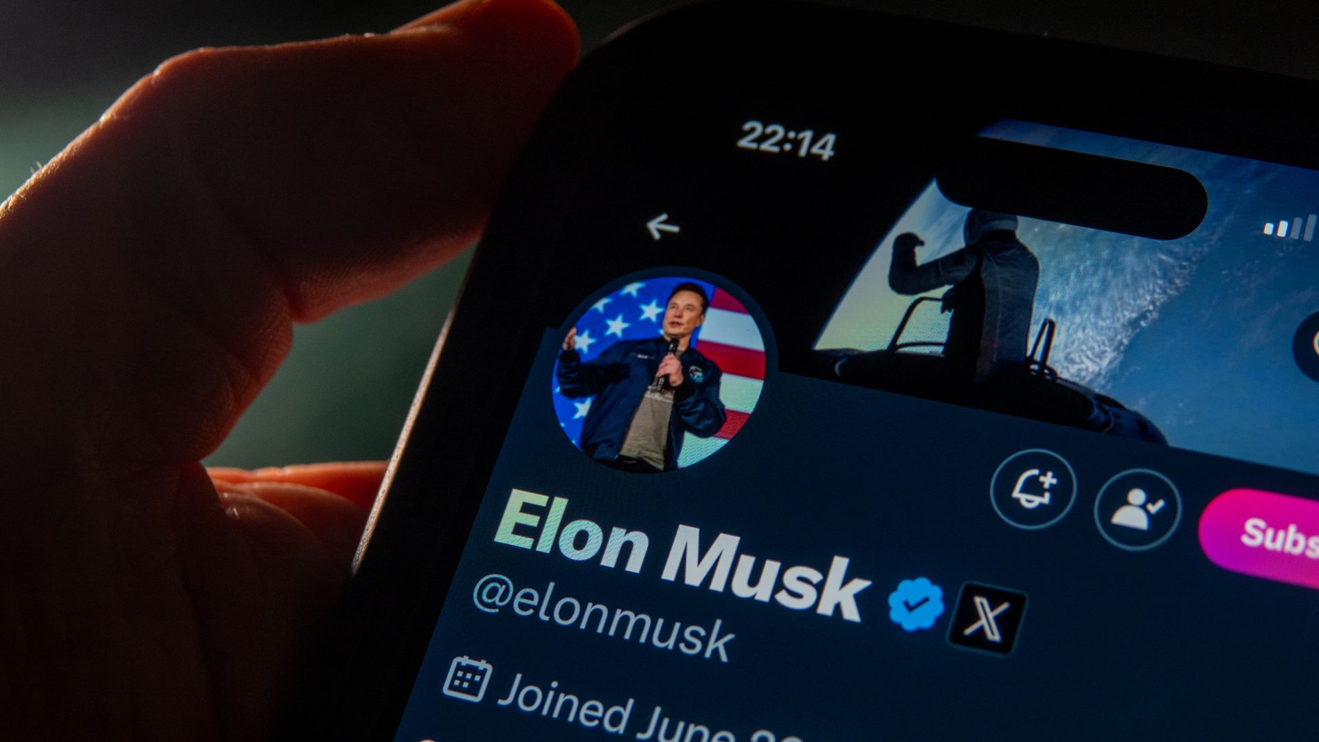 Elon Musk's profile page on the X social media platform, seen on a phone in a user's hand.