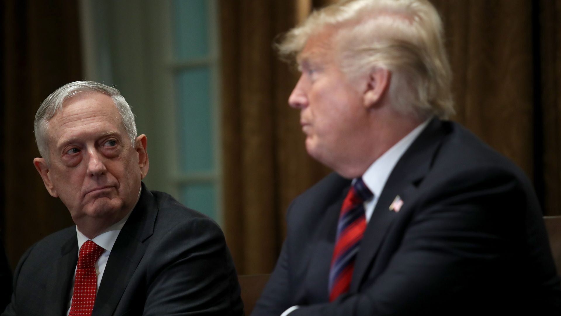 James Mattis and Trump sit side-by-side looking at each other