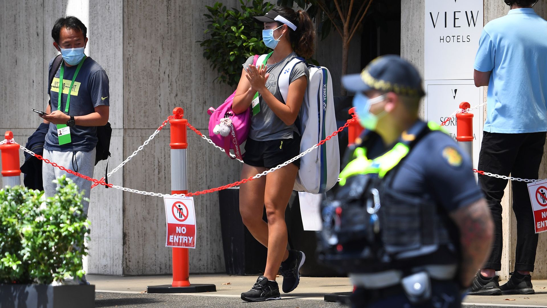 A tennis player (C) leaves the hotel for a training session in Melbourne on January 19