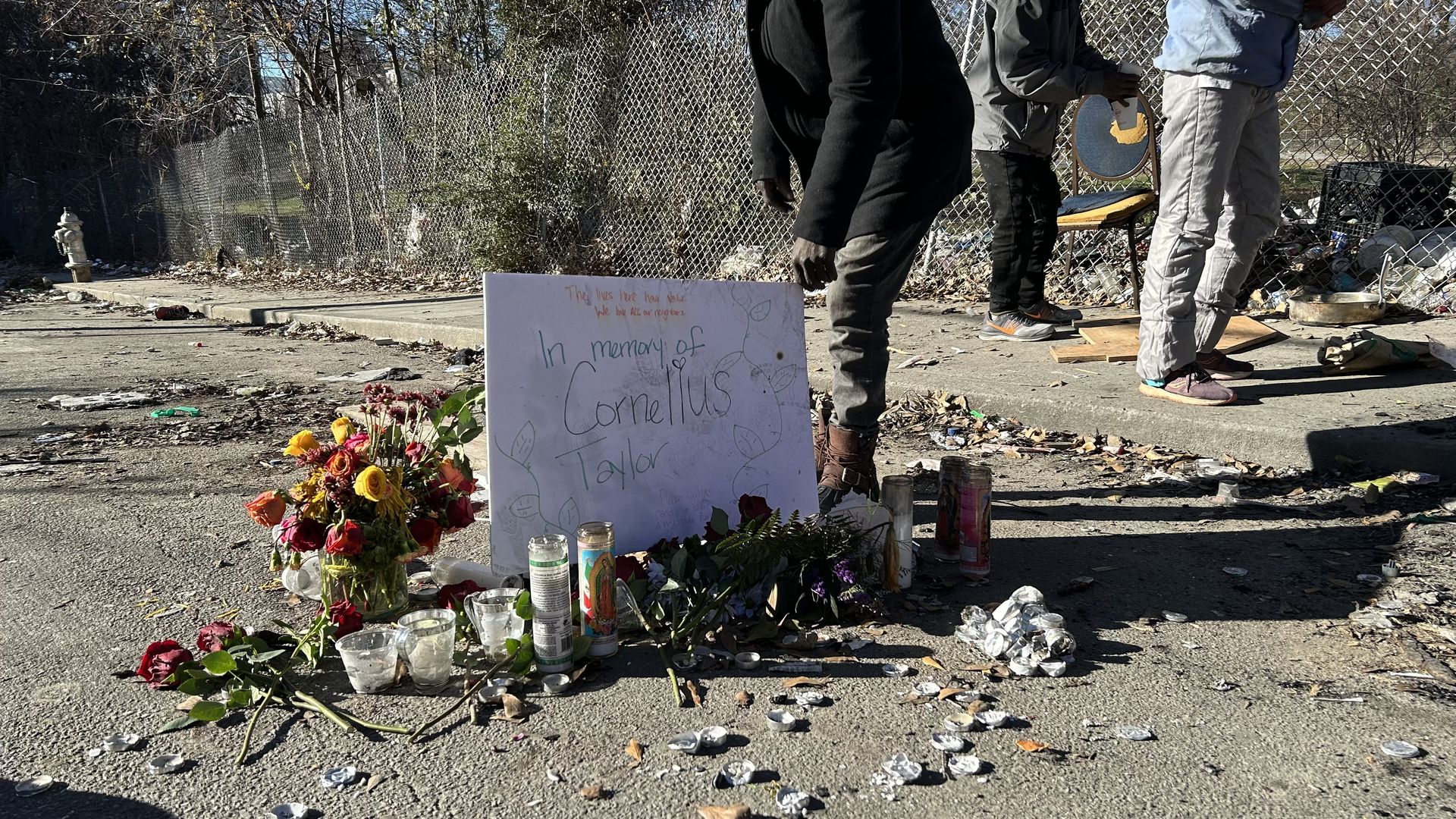 A man places a sign that memorializes a person named Cornelius Taylor