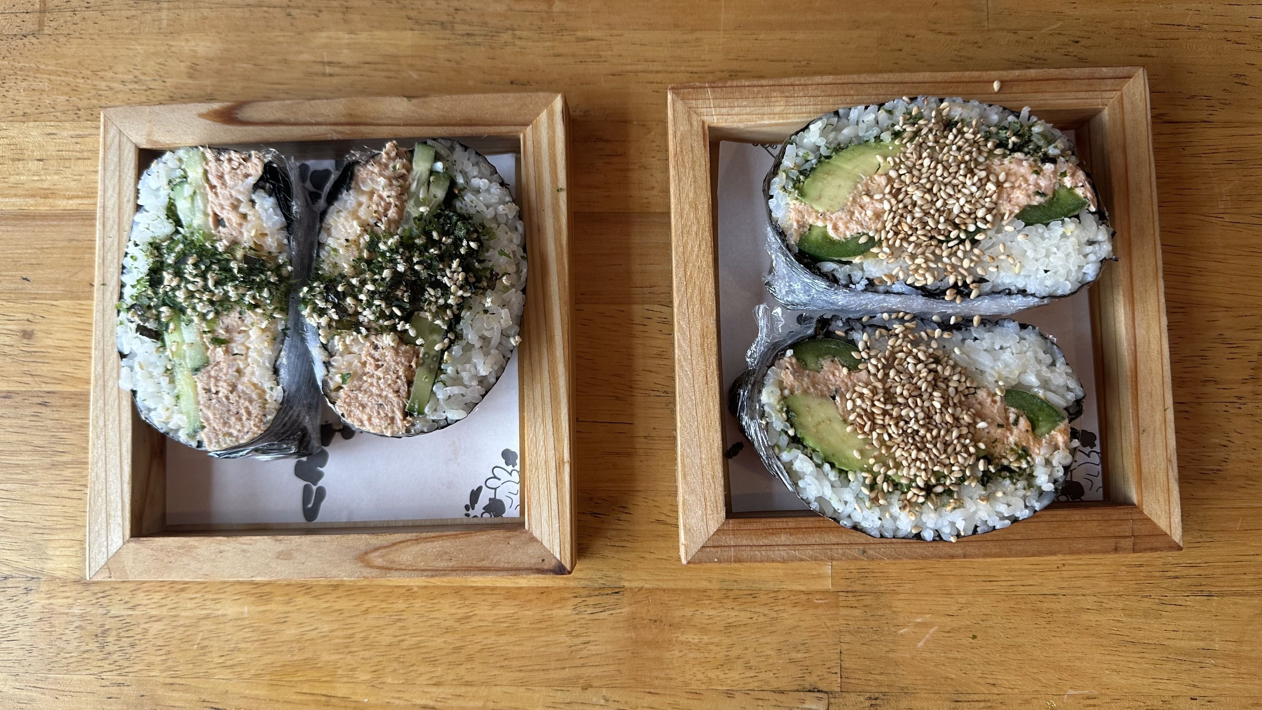 Sushi sandos sit side by side on a wooden tabletop.
