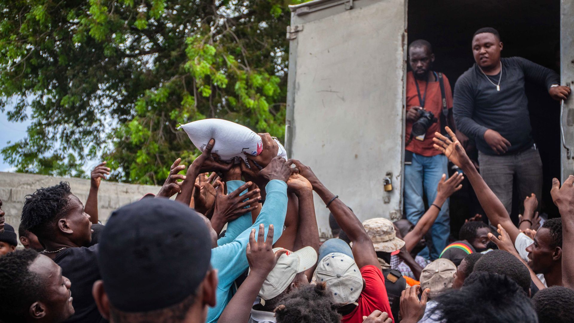 Haitians quarrel over a bag of food as part of the humanitarian aid