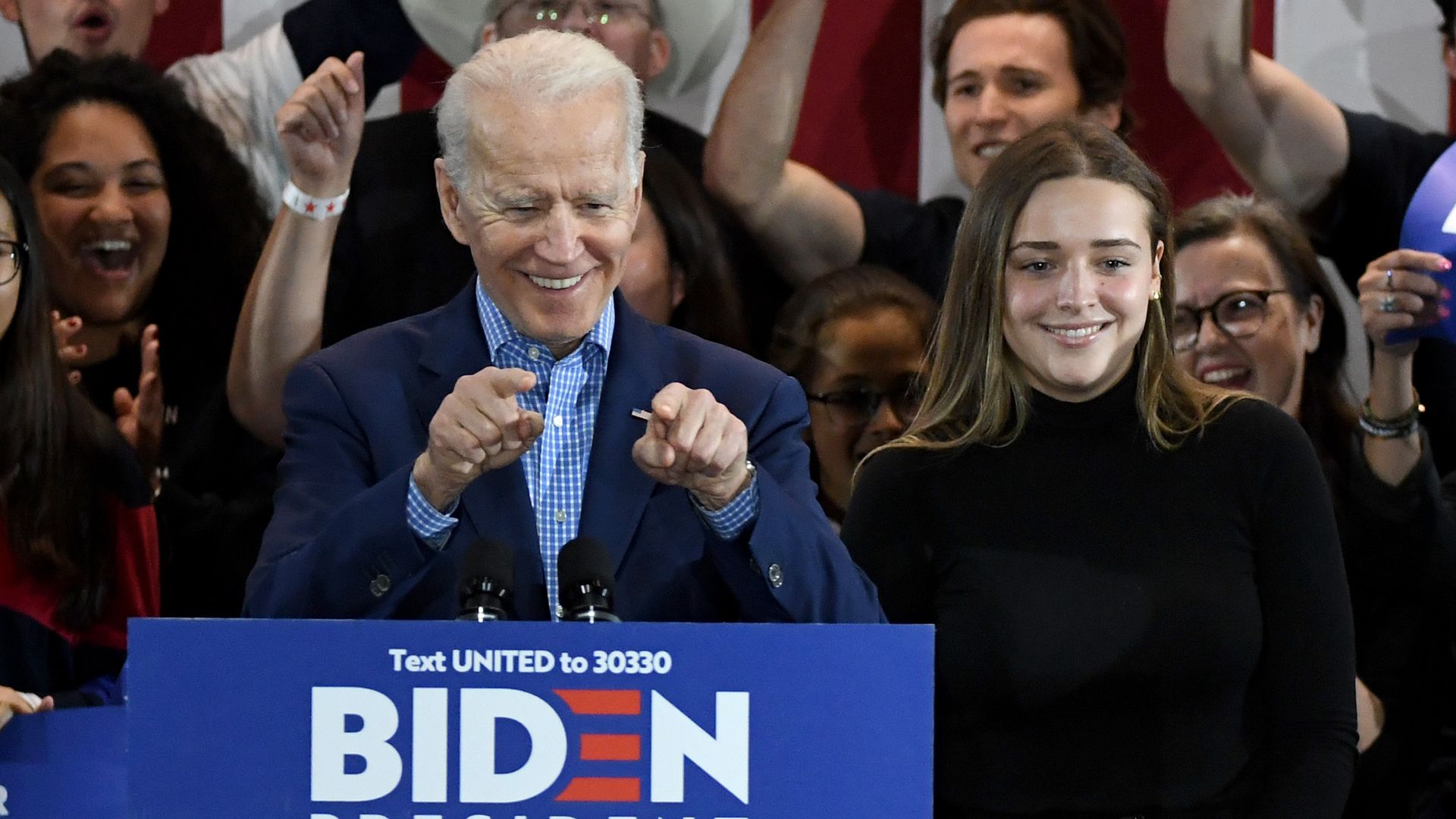 Joe Biden at a podium pointing at the crowd.