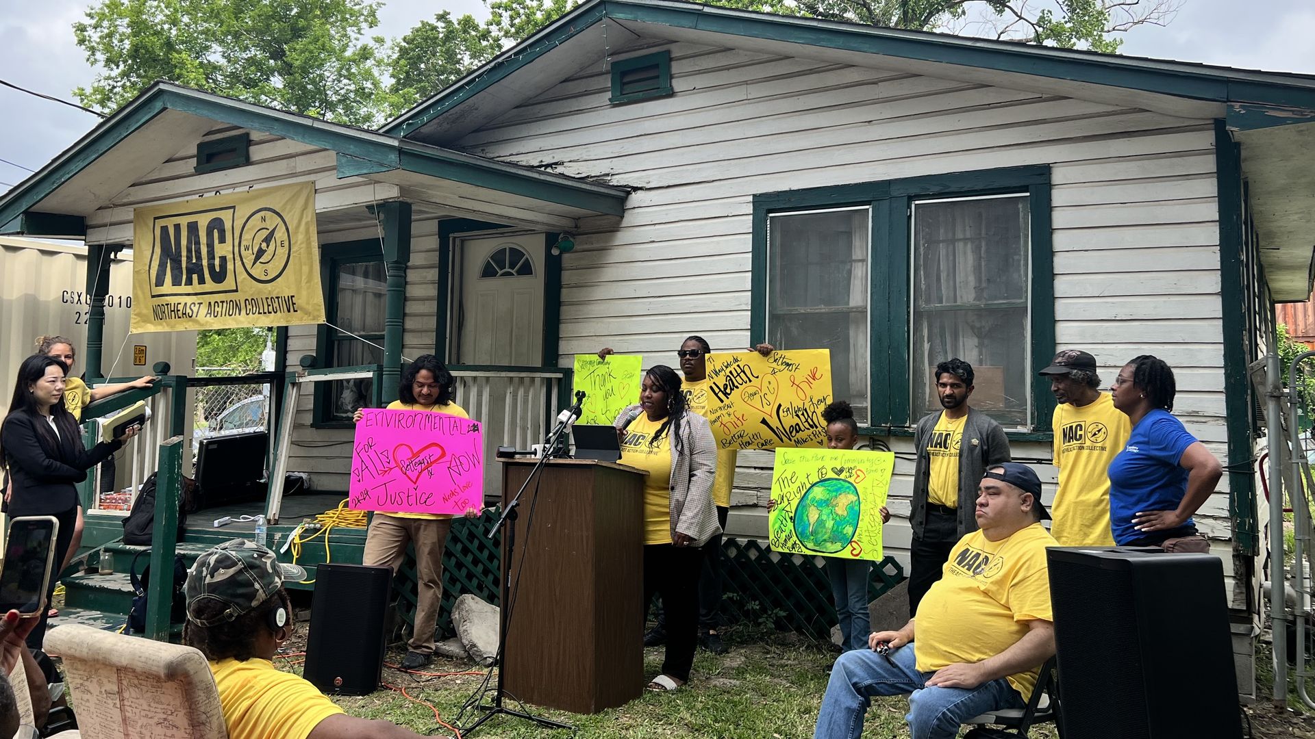 Photo of a group of people in yellow shirts in front of a home. 