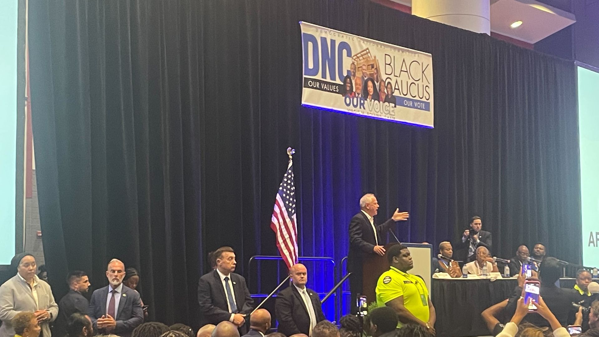 Walz on a stage that says DNC black caucus