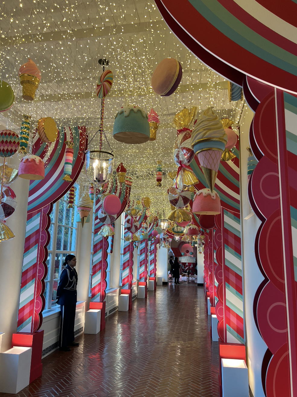 A hallway in the White House decorated with large pieces of candy hanging from the ceiling. 