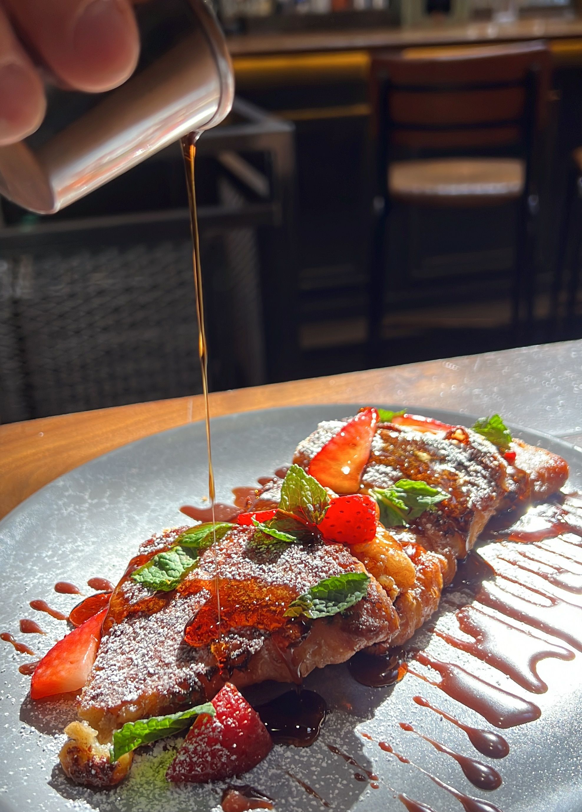 syrup pouring over french toast with strawberries
