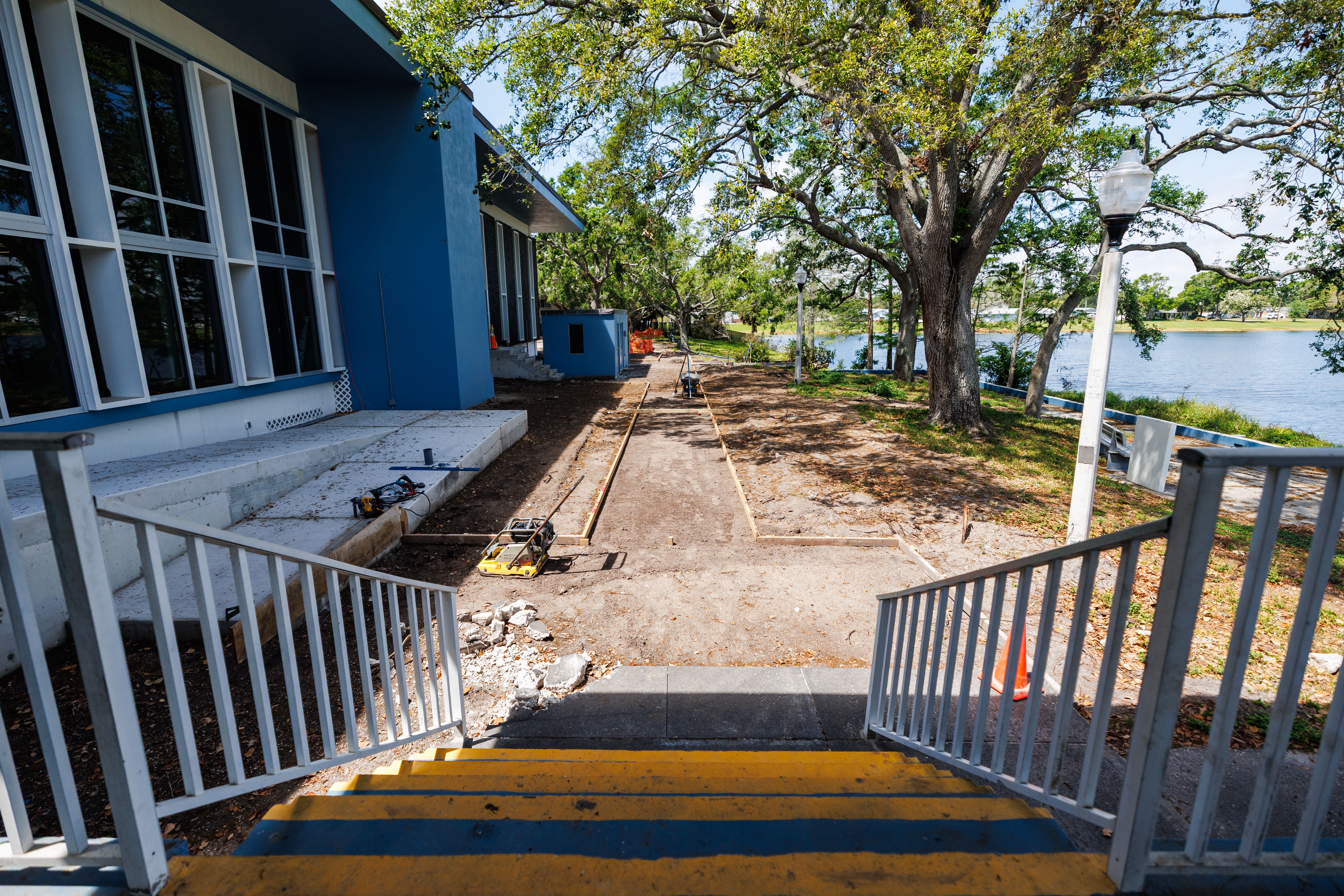 A staircase leads into a grassy area with a large tree and a view of a lake.