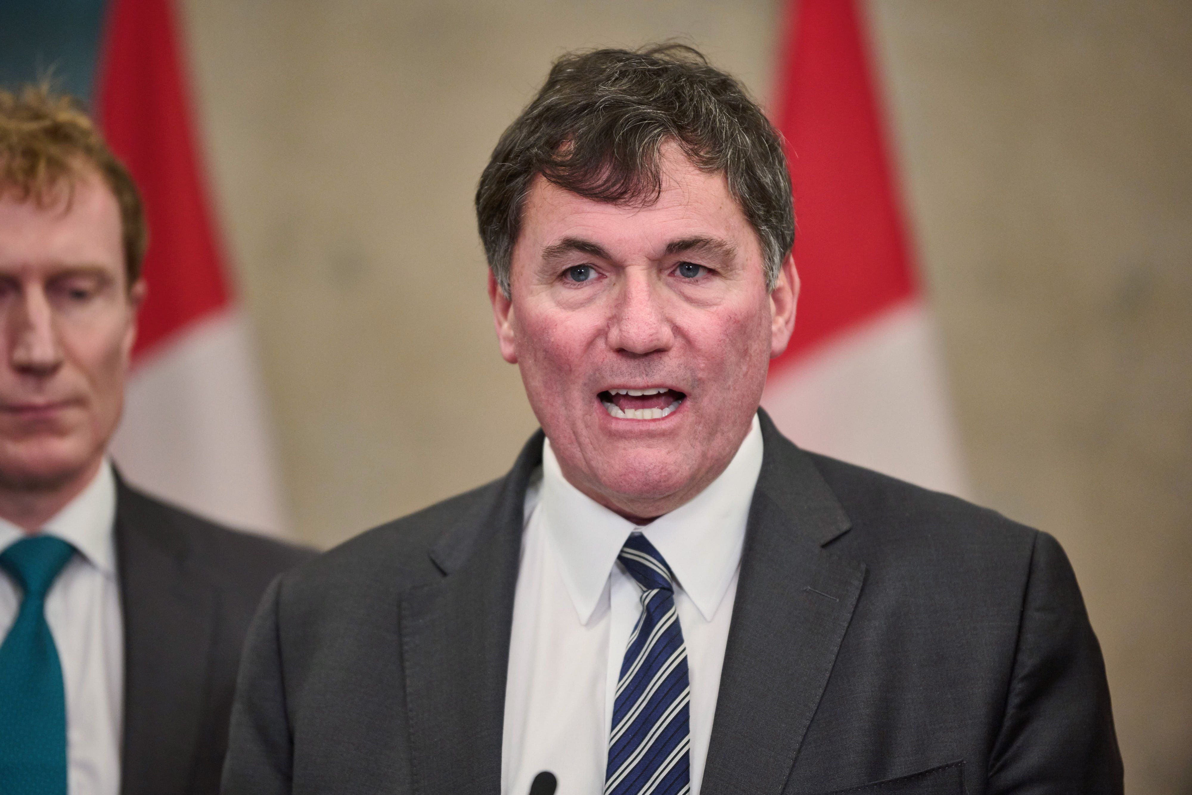 Dominic LeBlanc speaks with a flag behind him