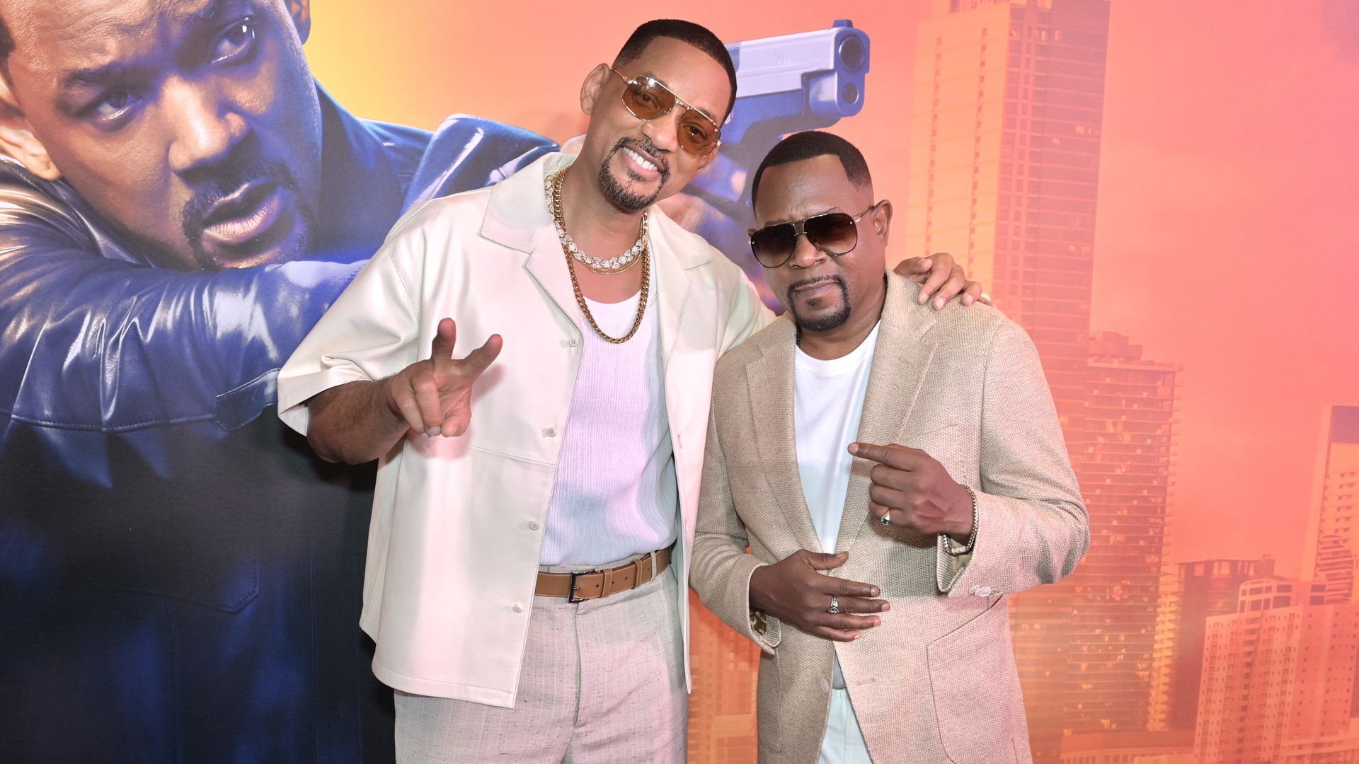 two actors in sunglasses, Will Smith and Martin Lawrence, standing in front of a large movie poster