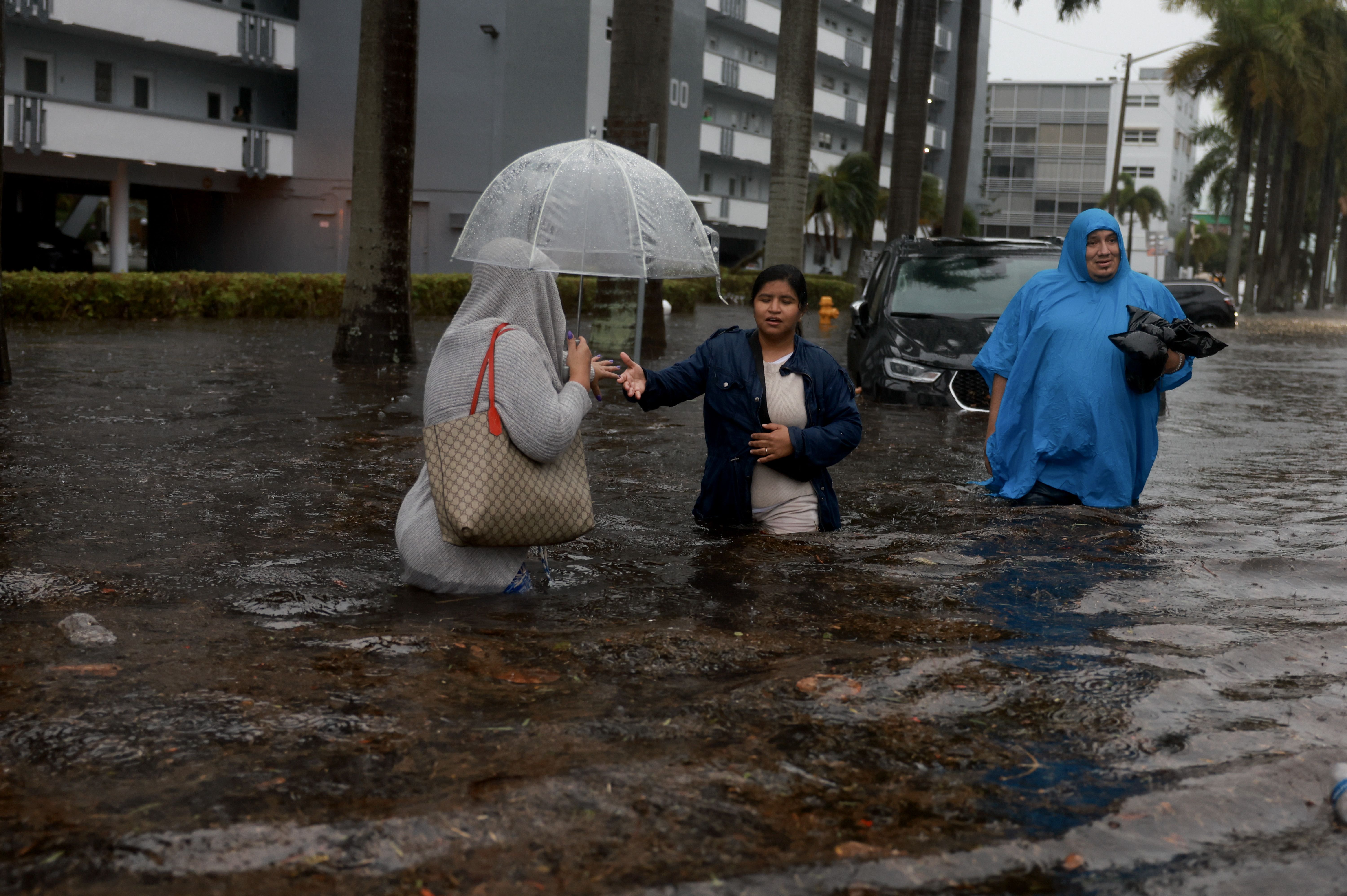 People walk through a flooded street on June 12, 2024, in Hollywood, Florida. As tropical moisture passes through the area, areas have become flooded due to the heavy rain. 