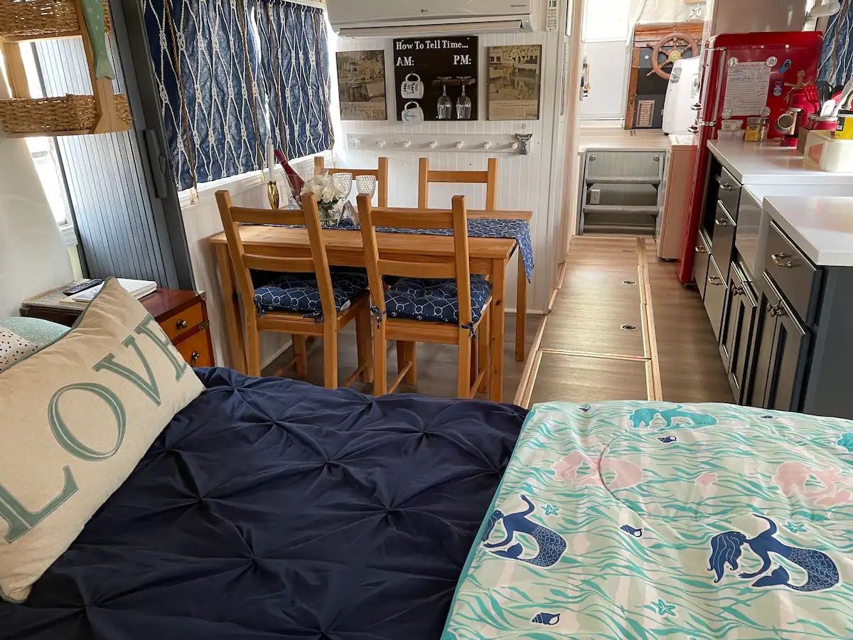 A bed with mermaid-print sheets and a kitchen table