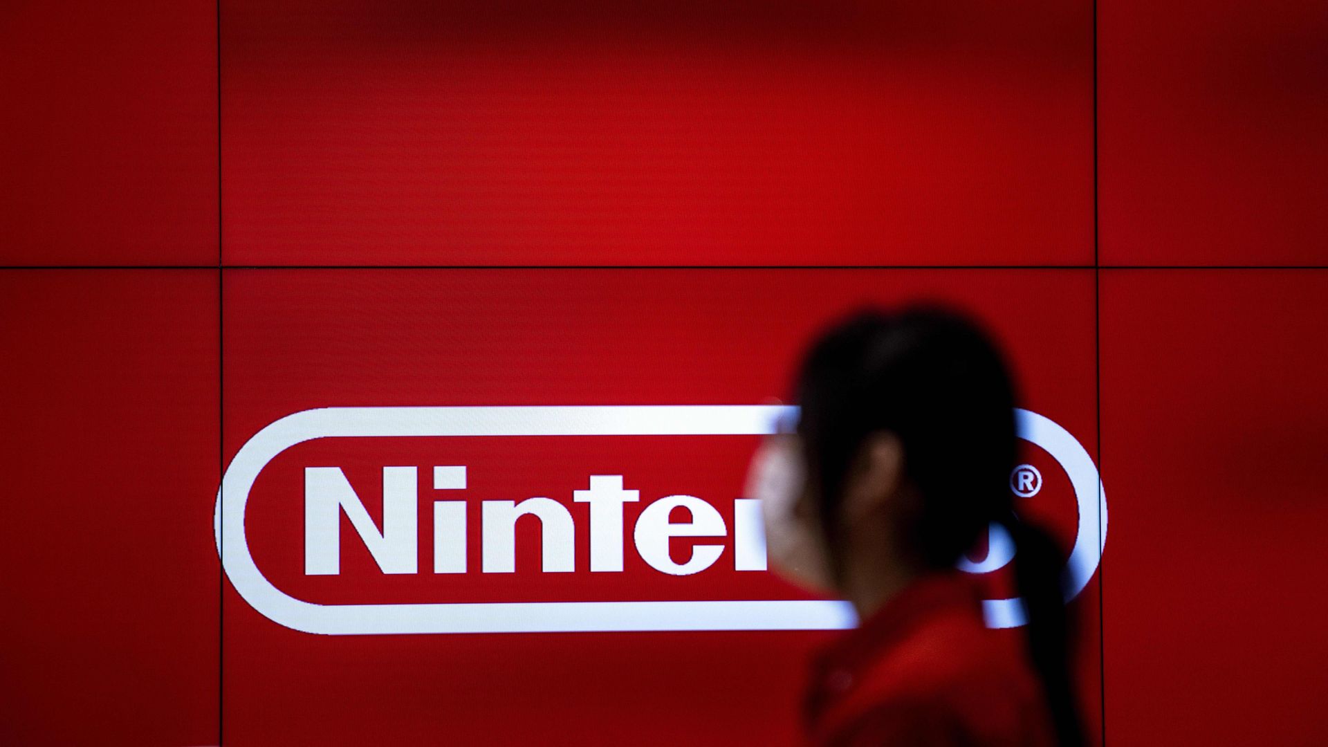 A woman in profile standing in front of the Nintendo logo