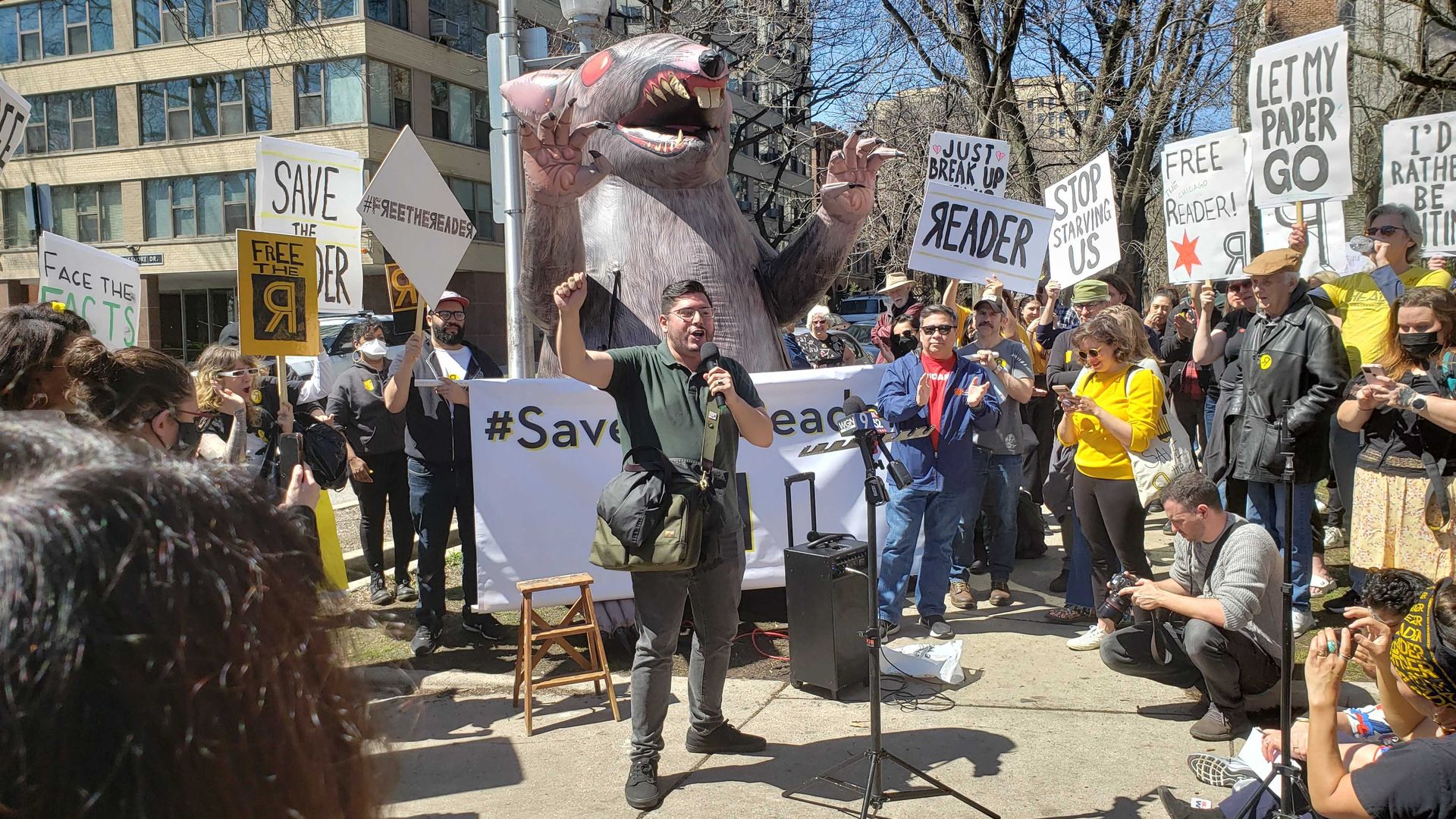 Guy at a rally with a rat and signs.