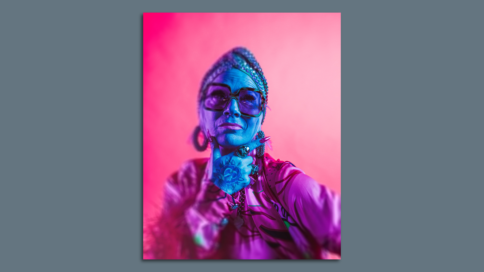 Portrait of a woman with a blue face, tattoos and glasses.