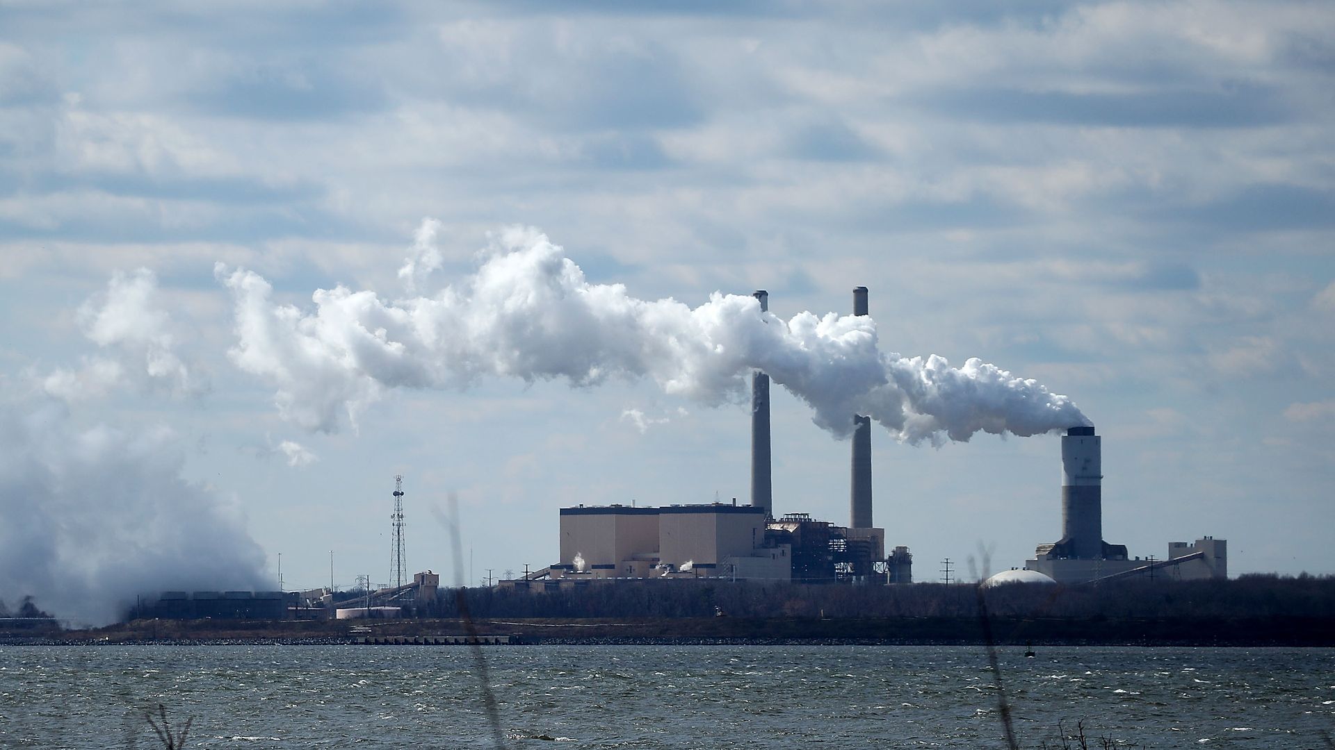 fumes coming out of a smoke stack at a coal plant on a river